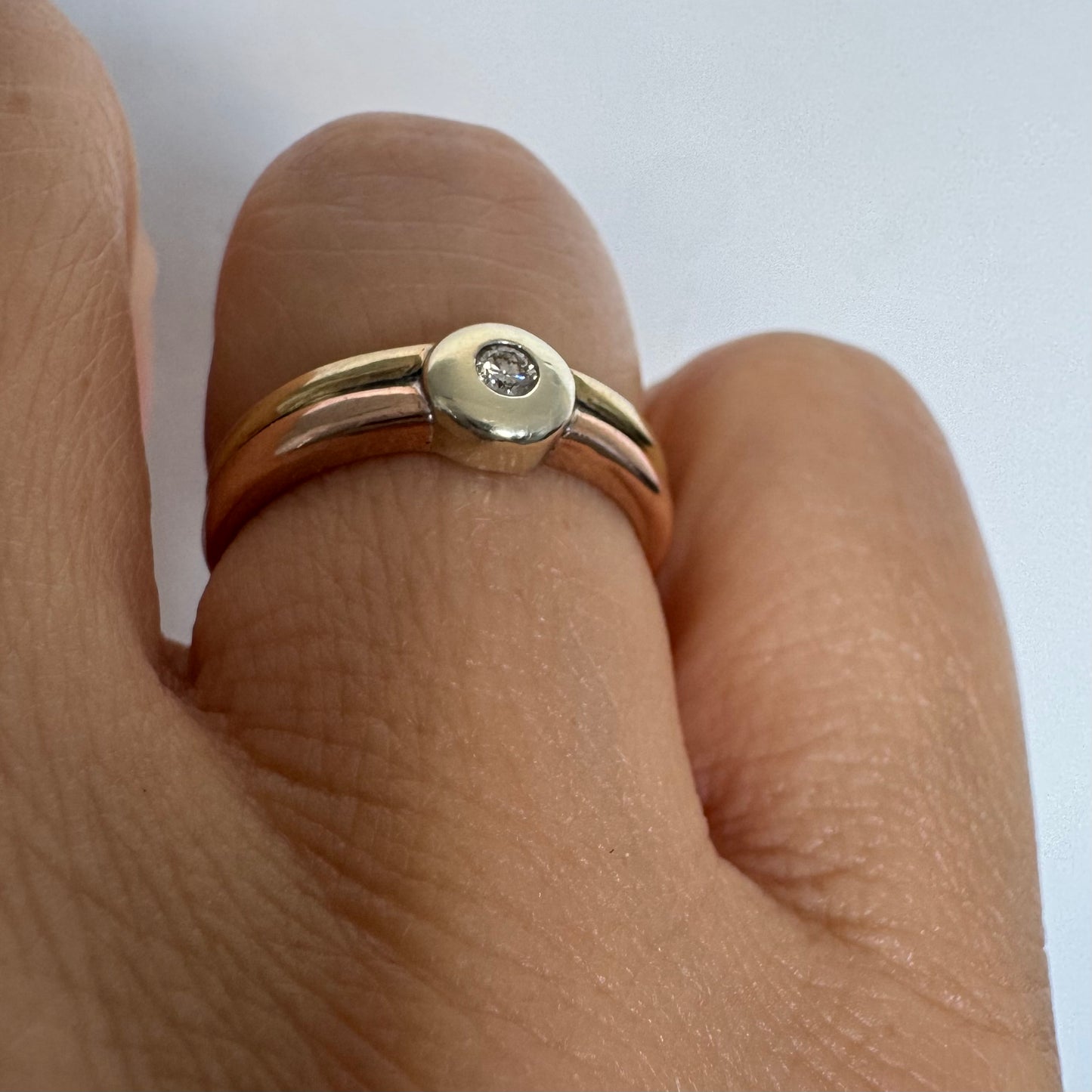 טבעת זהב 10 קראט בעיצוב מינימליסטי ונקי, משובצת יהלום מרכזי במסגרת חלקה (Bezel).