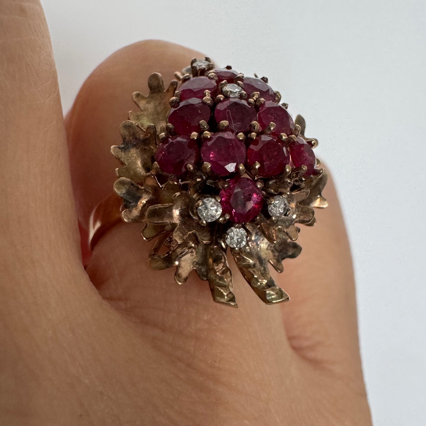 14K gold ring set with a vibrant cluster of deep red rubies and sparkling diamonds.