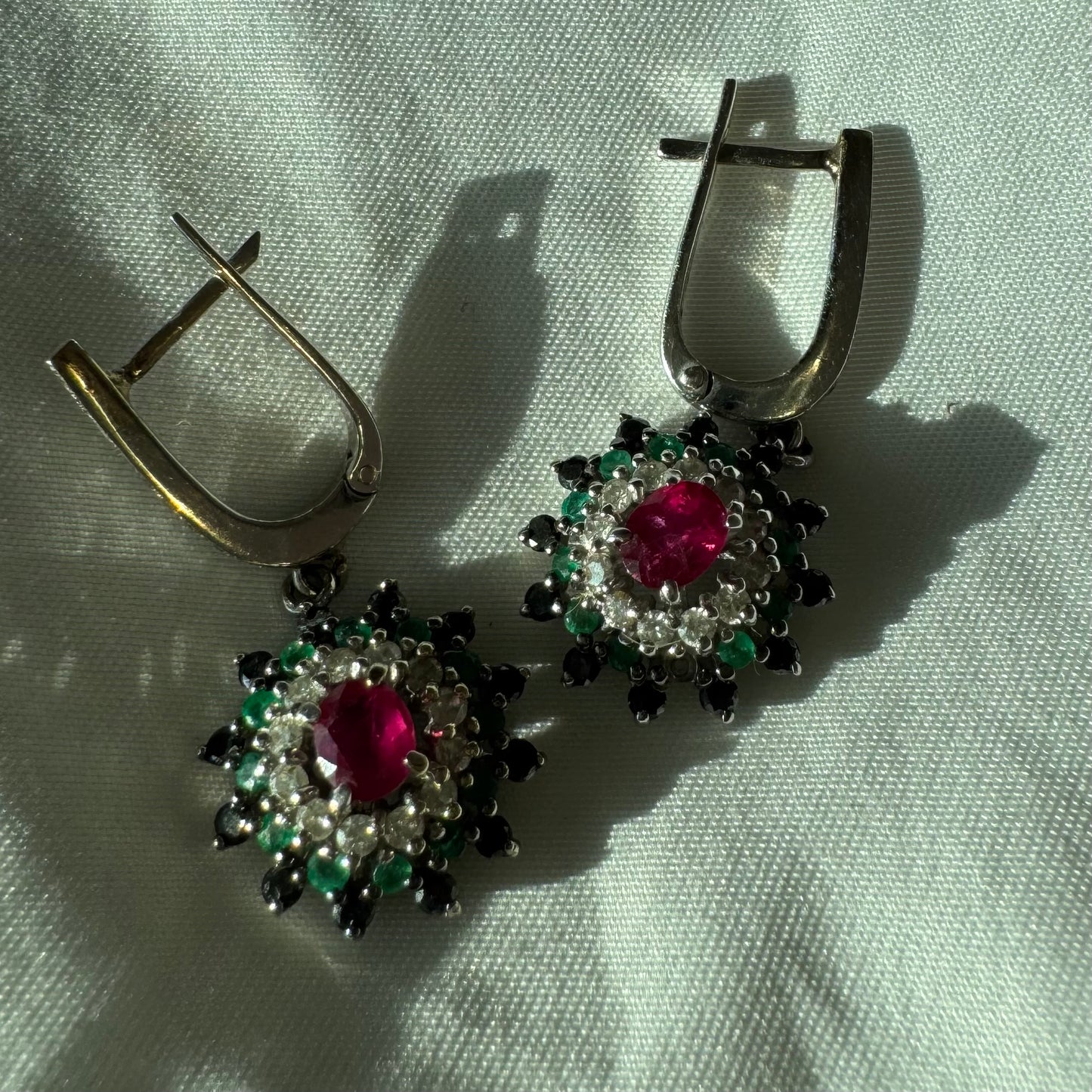 14K white gold drop earrings set with white and black Diamonds, Emeralds and a central Ruby