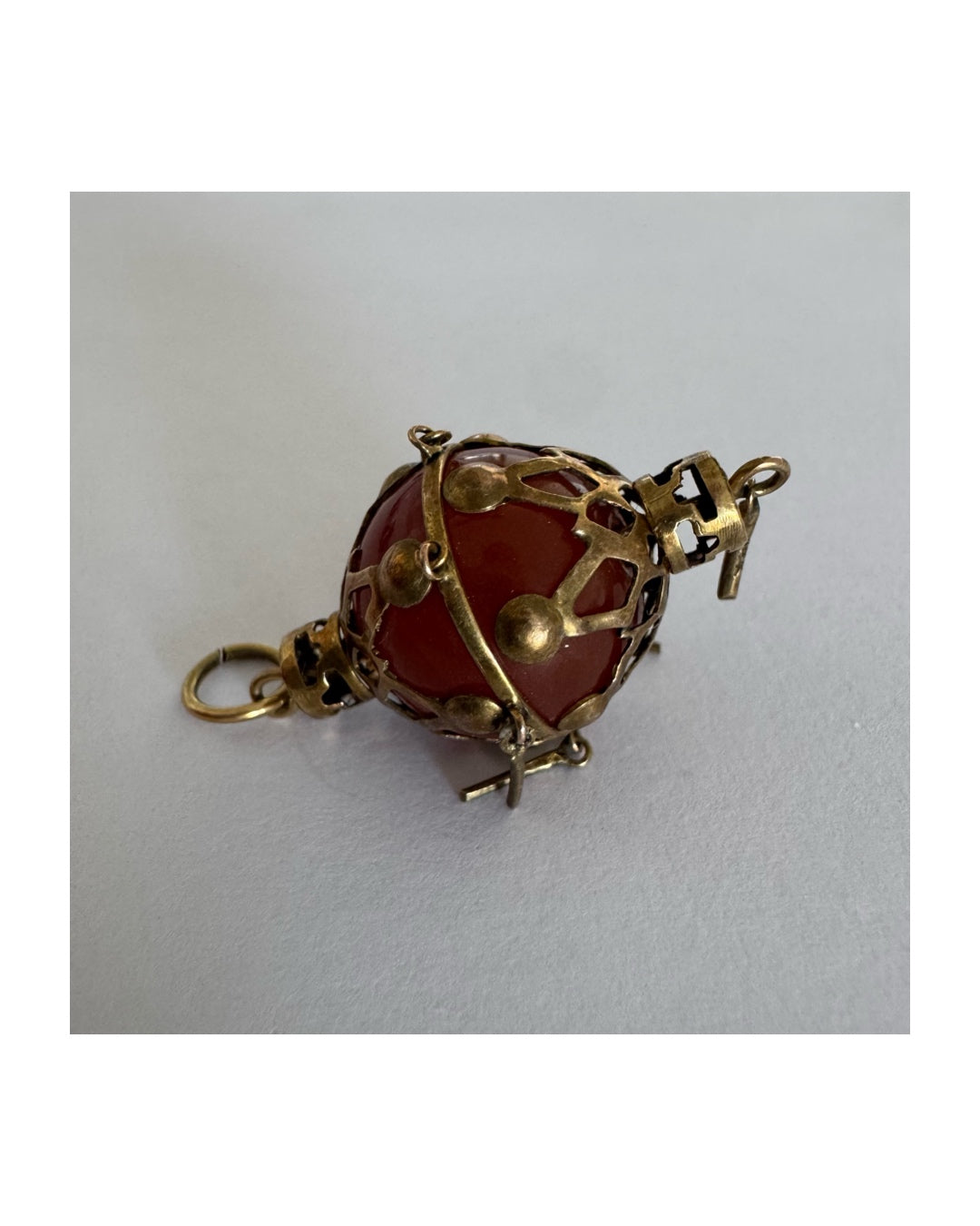 9K gold pendant set with a deep red stone in an intricate openwork design.