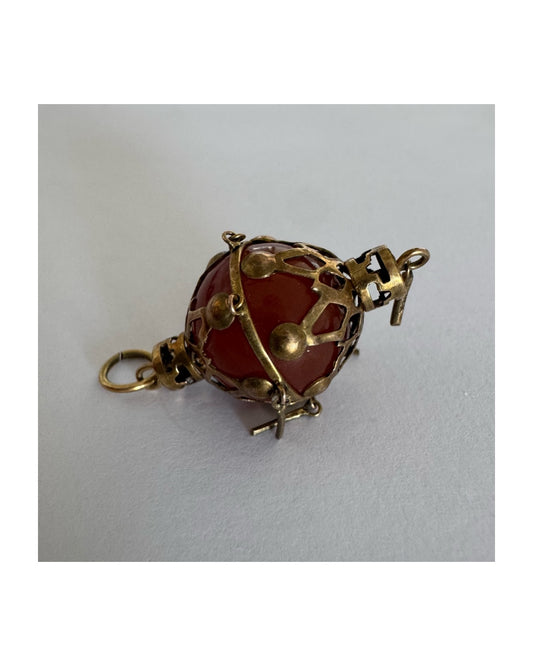 9K gold pendant set with a deep red stone in an intricate openwork design.