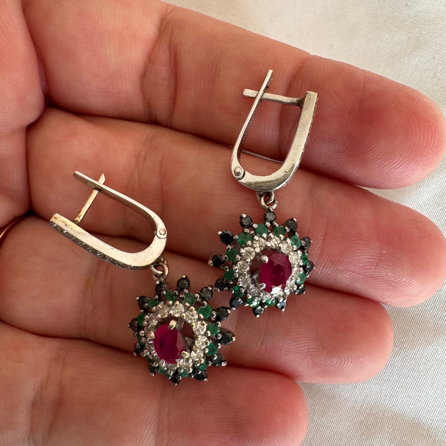 14K white gold drop earrings set with white and black Diamonds, Emeralds and a central Ruby