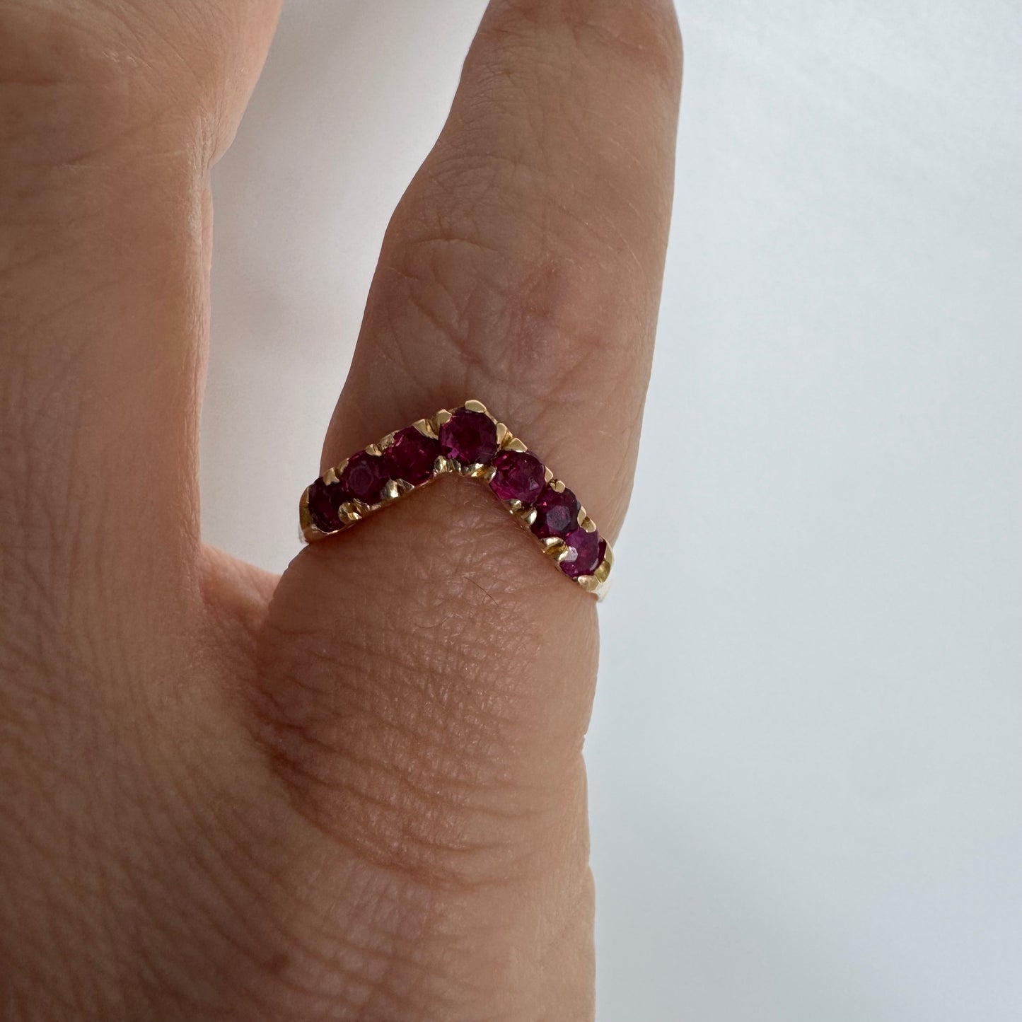 18K gold ring set with vivid red rubies in a distinctive V-shaped design.