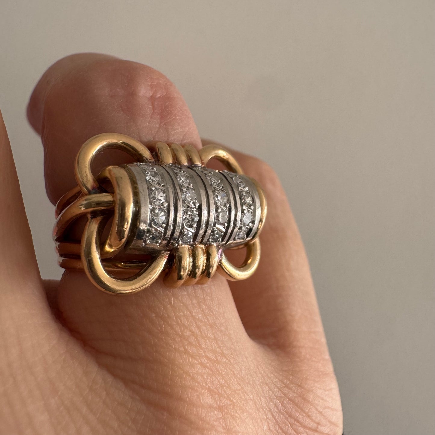 טבעת זהב צהוב ולבן 18 קראט עם מרכז בצורת חבית, משובצת יהלומים נוצצים.