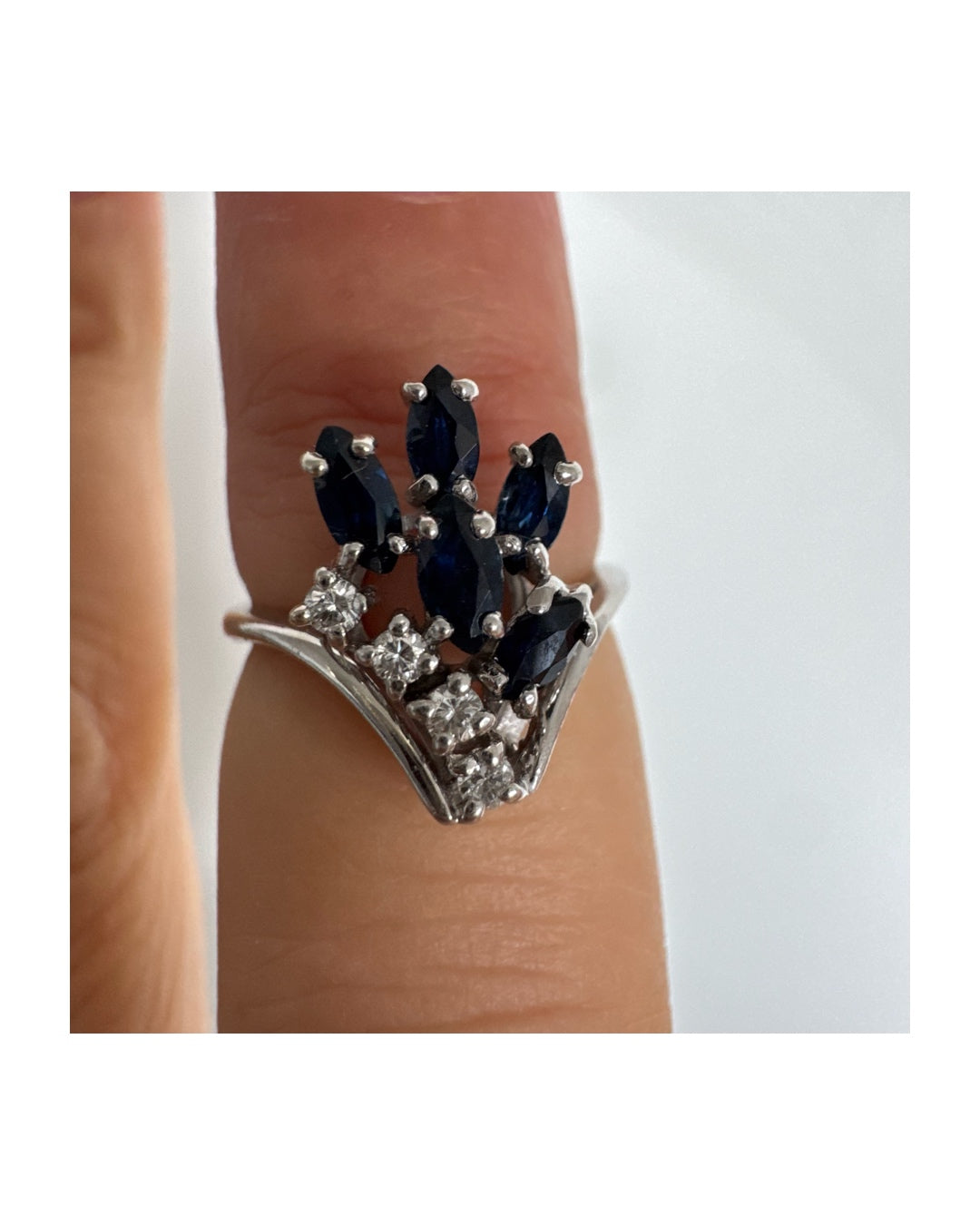 טבעת זהב לבן 14 קראט משובצת אבני ספיר כחולות בחיתוך מרקיזה ויהלומים, היוצרים מראה אלגנטי ודינמי.