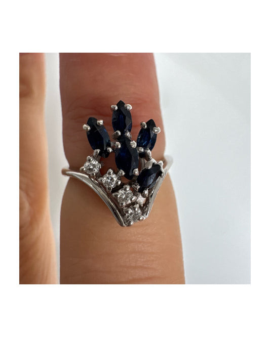 טבעת זהב לבן 14 קראט משובצת אבני ספיר כחולות בחיתוך מרקיזה ויהלומים, היוצרים מראה אלגנטי ודינמי.