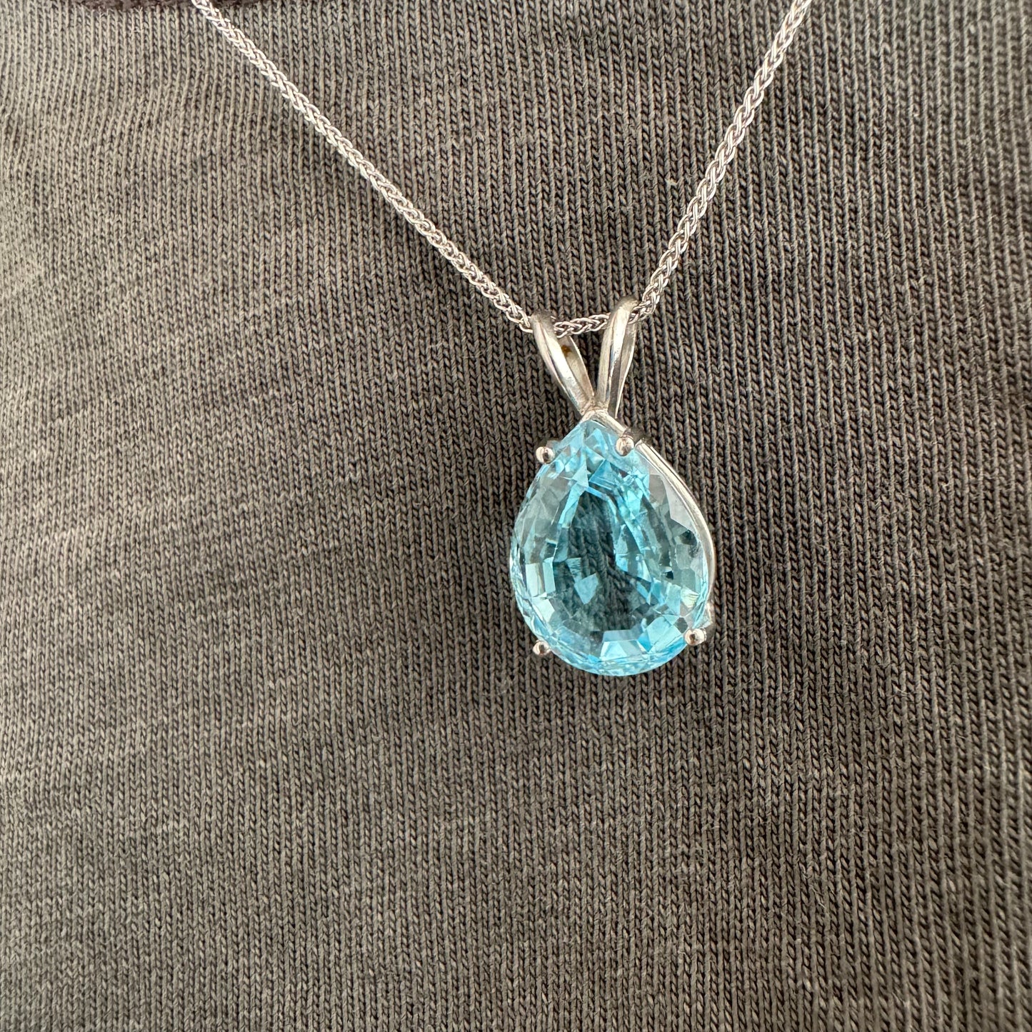 תליון זהב לבן 14 קראט המשובץ אבן טופז כחולה בחיתוך טיפה.