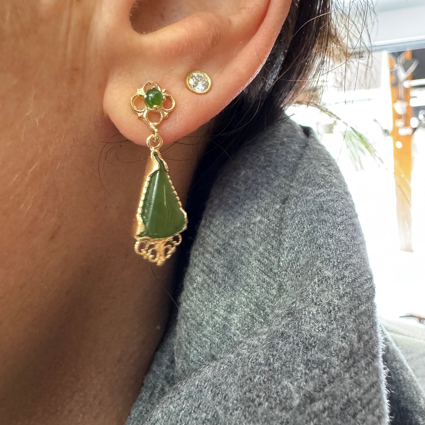 עגילי זהב צהוב 14 קראט משובצים אבני ג׳ייד ירוקות בגוון עמוק בחיתוך משולש.