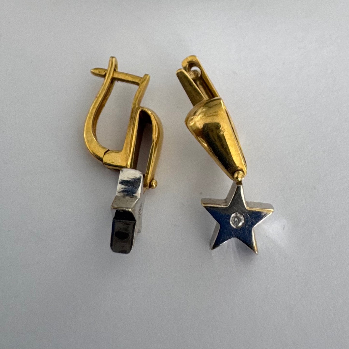 עגילי זהב 18 קראט בעיצוב כוכב ייחודי, המשלבים זהב צהוב ולבן ומשובצים ביהלום במרכז כל כוכב.