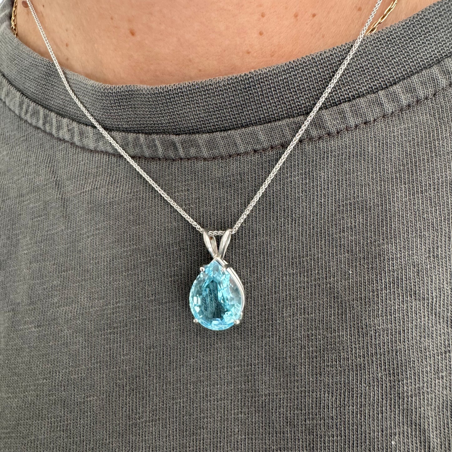 תליון זהב לבן 14 קראט המשובץ אבן טופז כחולה בחיתוך טיפה.