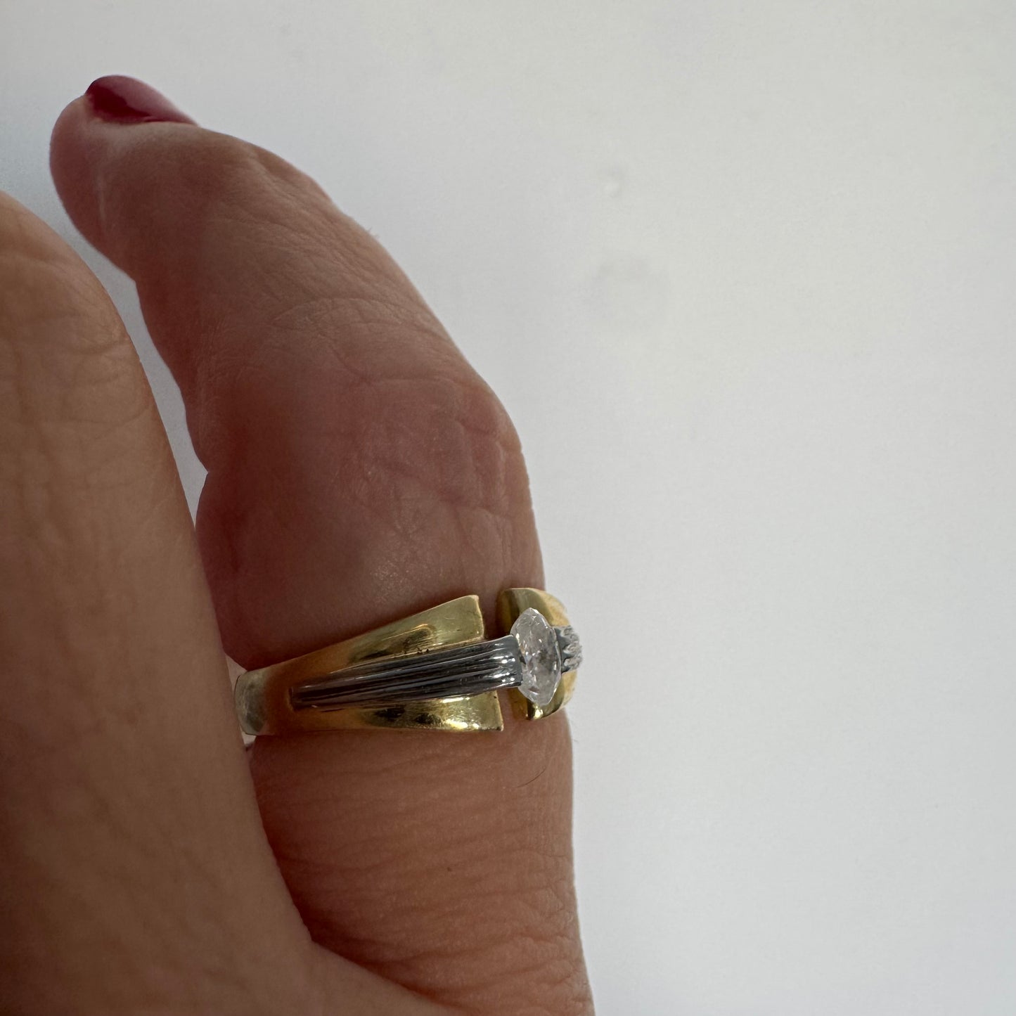 טבעת זהב 18 קראט בעיצוב דו-גוני של זהב צהוב ולבן, משובצת יהלום בחיתוך מרקיזה. 
