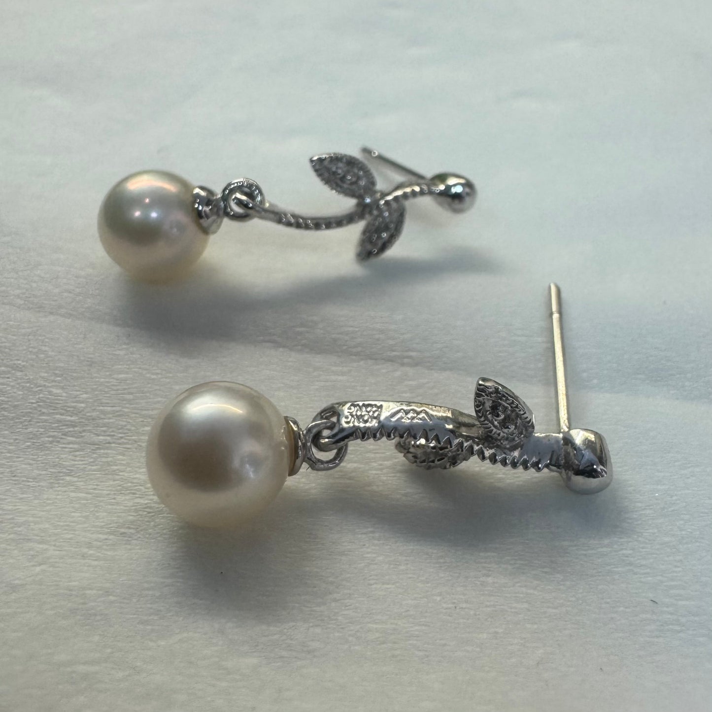 14K gold drop earrings designed with delicate leaf details, each holding a round white Pearl.