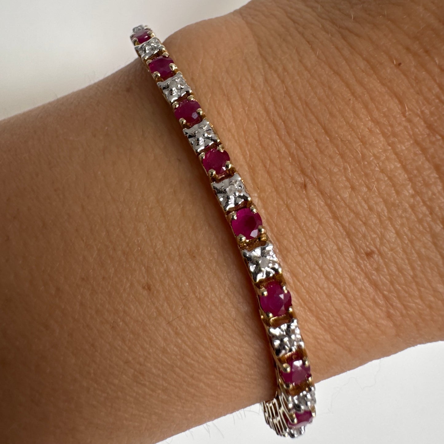 צמיד זהב צהוב 10 קראט משובץ אבני רובי בגוון אדום עמוק וביניהן יהלומים לבנים מנצנצים.