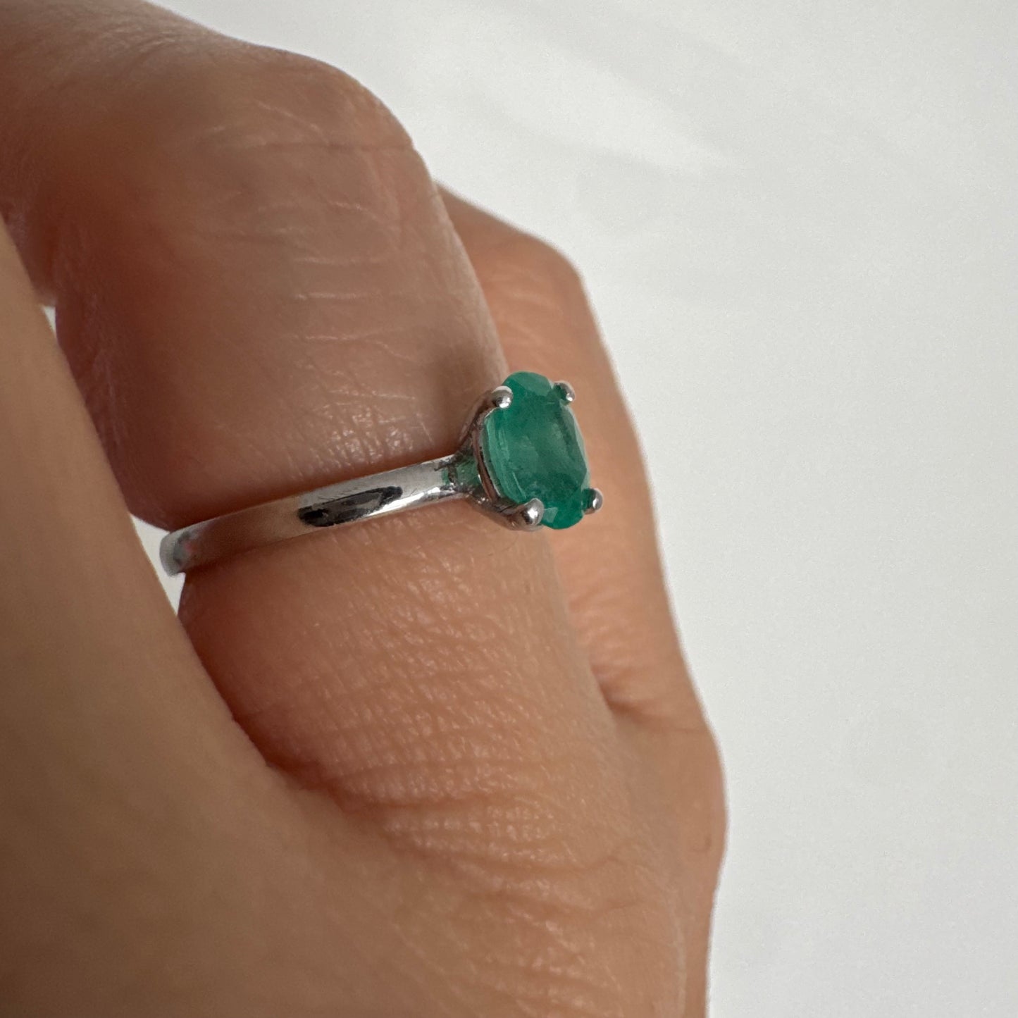 טבעת זהב לבן 14 קראט משובצת אבן אמרלד אובלית בגוון ירוק עשיר.