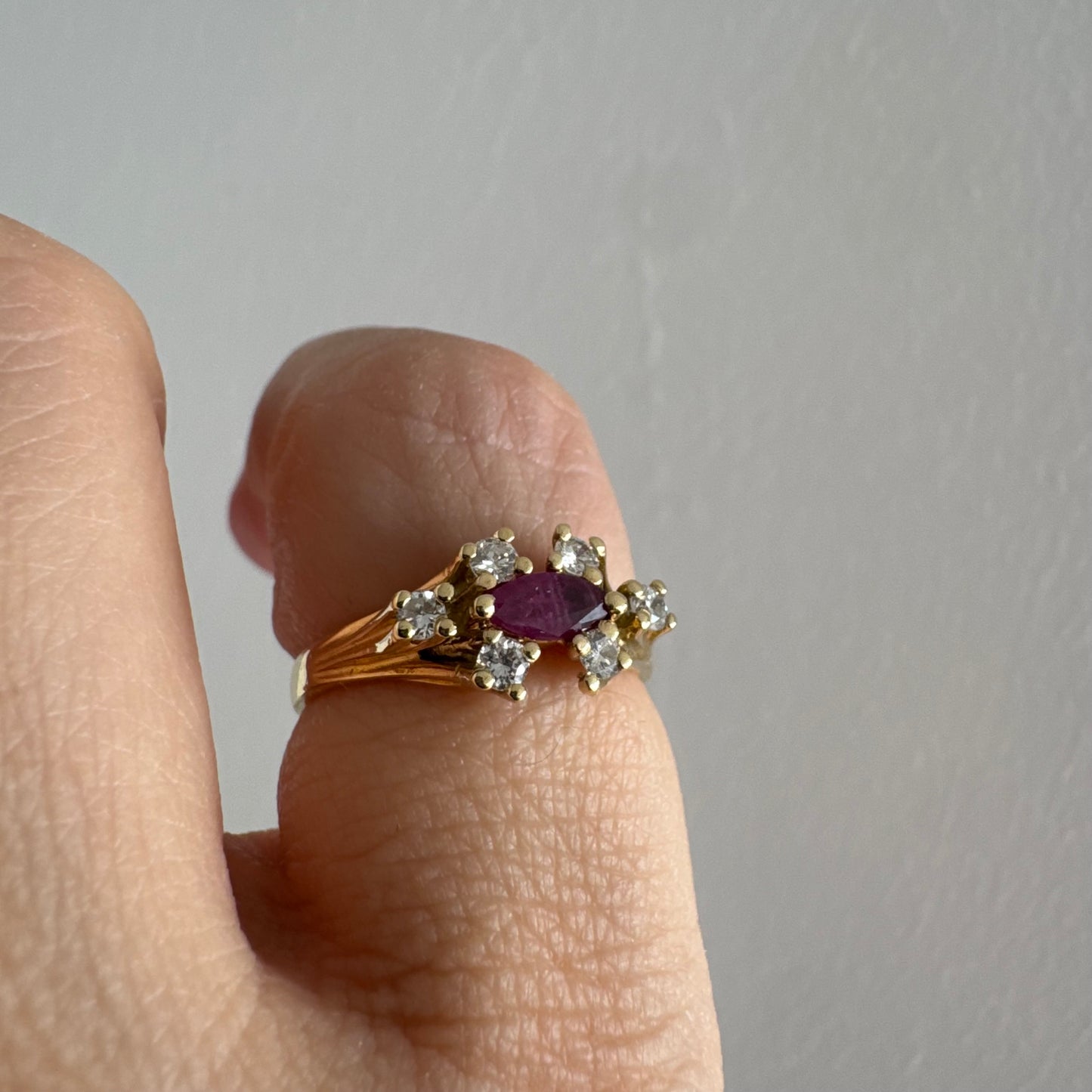 18K gold ring set with a marquise-cut Ruby accented by round Diamonds on each side.