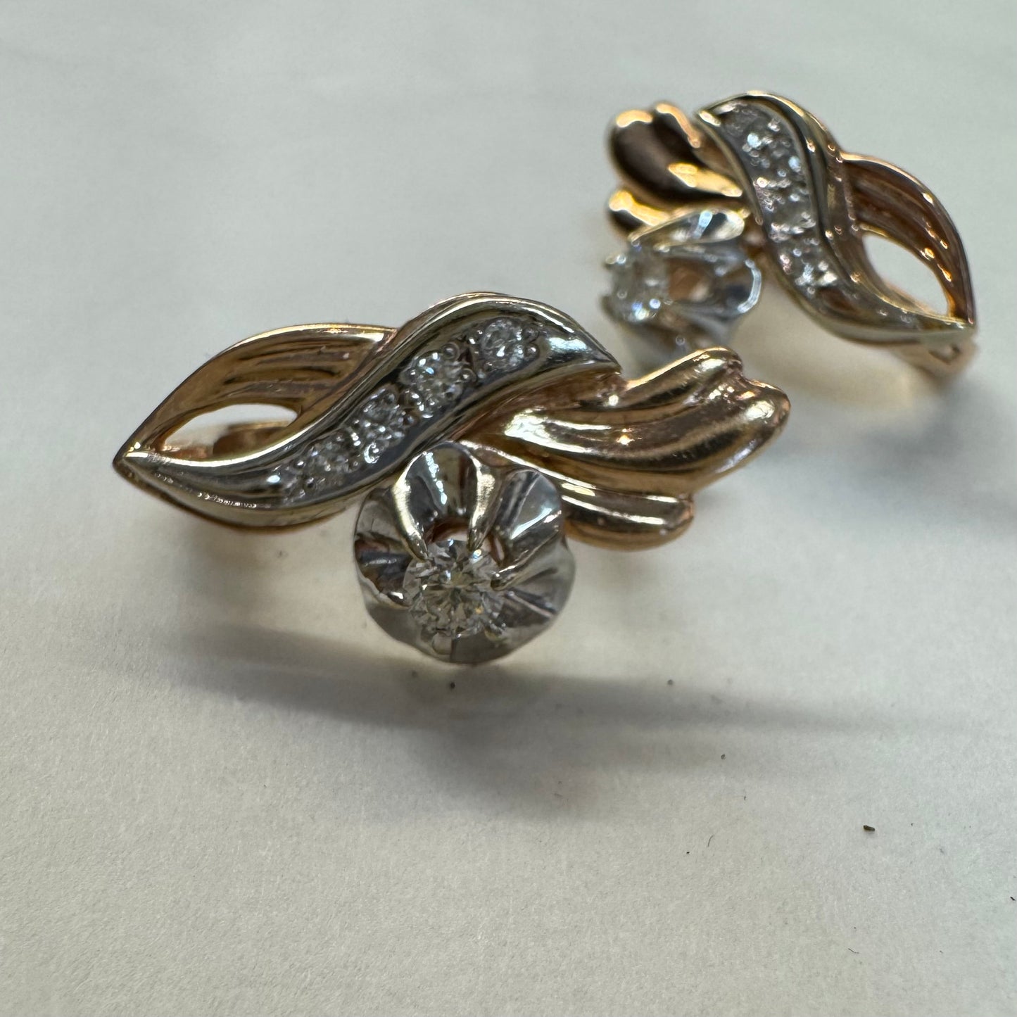 עגילי זהב 14 קראט בעיצוב מתעגל ואלגנטי המשובצים יהלומים נוצצים .