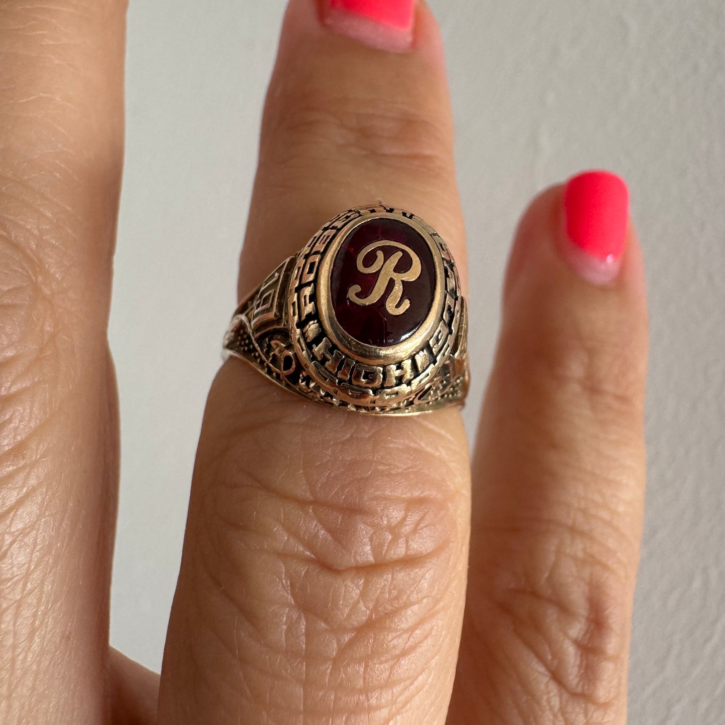 10K gold class ring featuring a rich red center stone engraved with the letter “R”.
