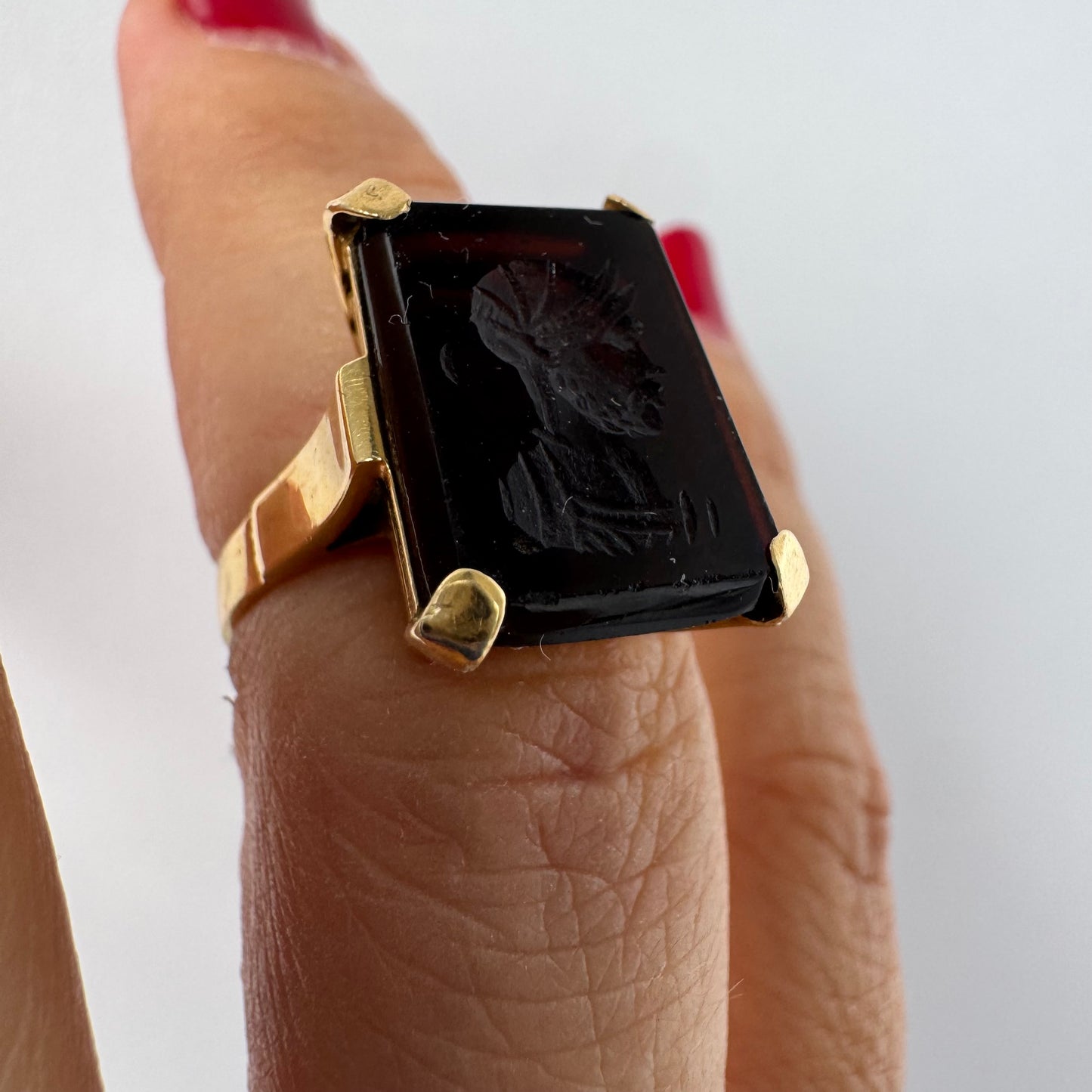 18K gold ring set with a carved dark stone featuring a classical warrior profile.