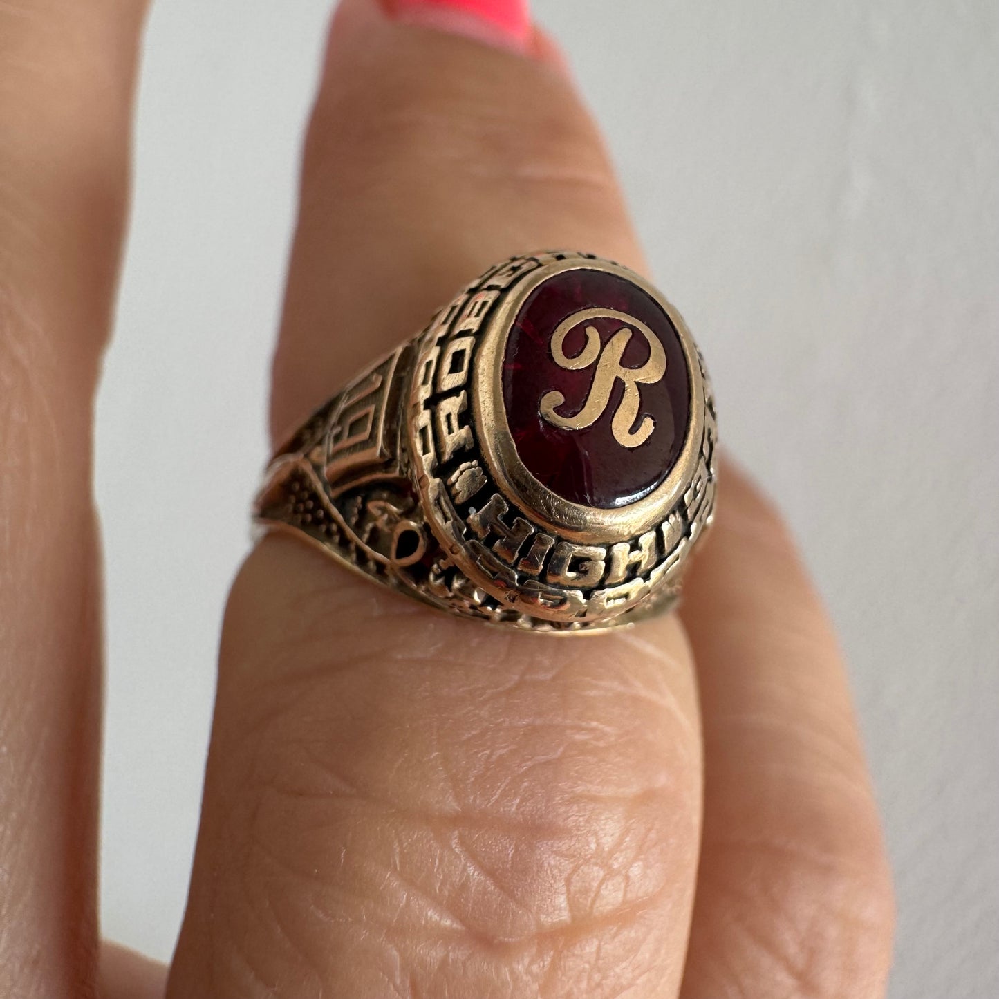 10K gold class ring featuring a rich red center stone engraved with the letter “R”.