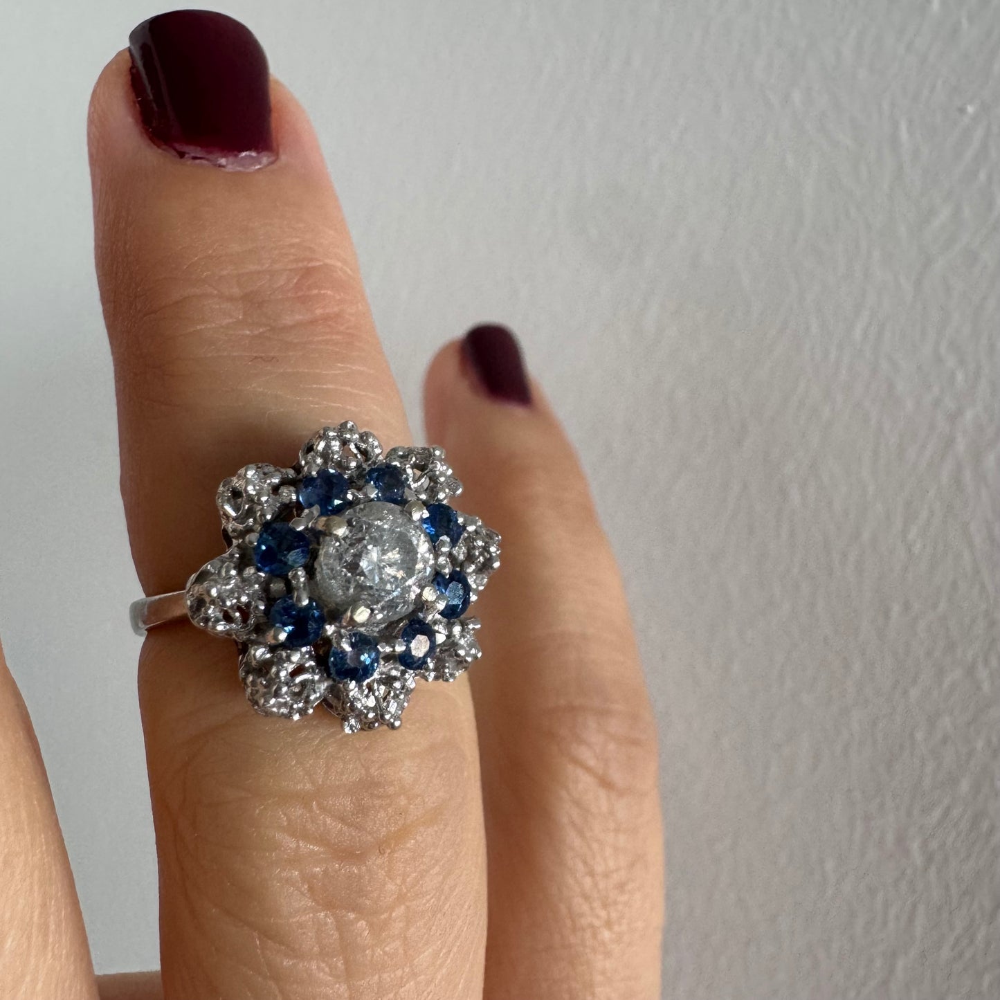 18K gold ring featuring a large round Diamond at the center, surrounded by a floral halo of purple -blue Tanzanite and & Diamonds.