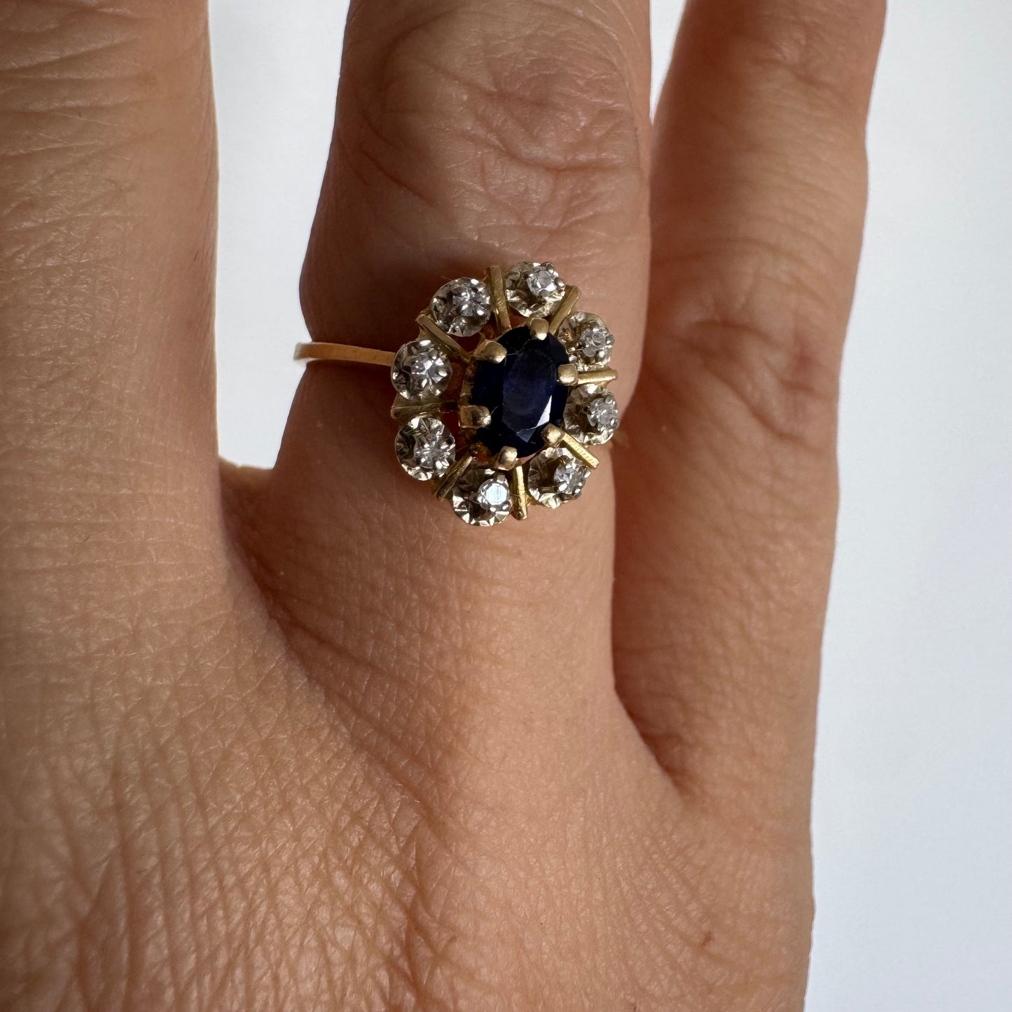 18K gold ring set with a natural blue Sapphire at its center, surrounded by a halo of sparkling Diamonds