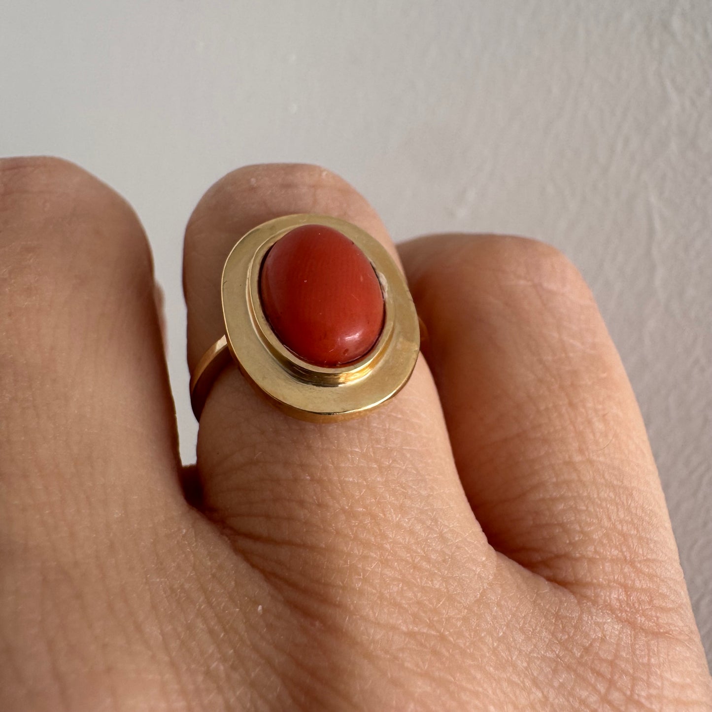 טבעת זהב 18 קראט משובצת אבן קורל אובלית בגימור קבושון, משובצת במסגרת חלקה ונקייה.