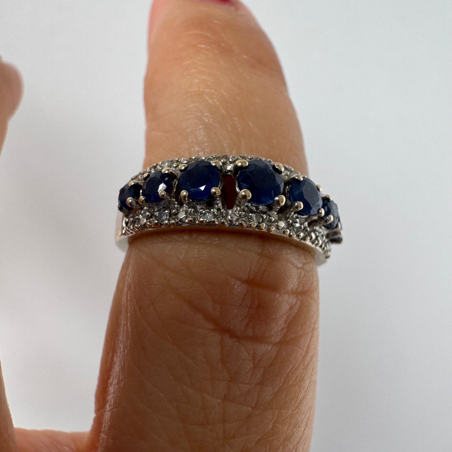 18K gold ring set with deep blue sapphires in a classic round cut, framed by two shimmering rows of brilliant Diamonds.