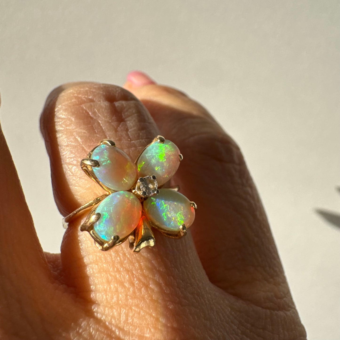 טבעת זהב 14 קראט בעיצוב פרח, משובצת ארבע אבני אופל בחיתוך טיפה ובמרכז יהלום טבעי.