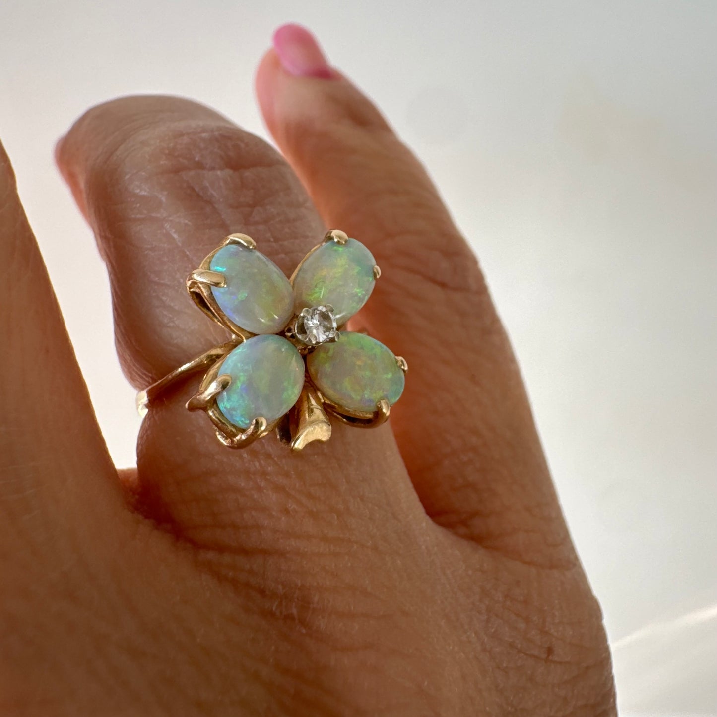 טבעת זהב 14 קראט בעיצוב פרח, משובצת ארבע אבני אופל בחיתוך טיפה ובמרכז יהלום טבעי.