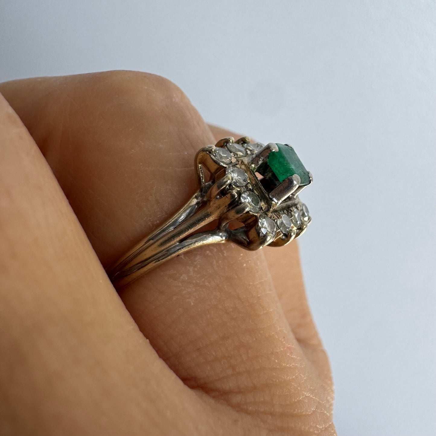 18K gold ring set with a vibrant square-cut Emerald surrounded by a sparkling halo of Diamonds.