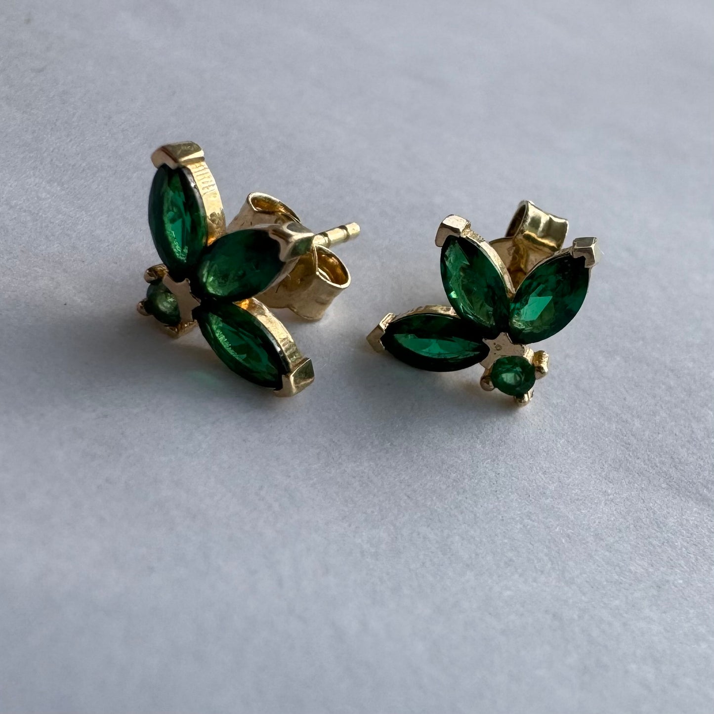 עגילים צמודיפ לאוזן מזהב 14 קראט, בעיצוב פרח עדין משובצים אבני אמרלד בחיתוך מרקיזה היוצר מראה אלגנטי, נקי ועל-זמני.