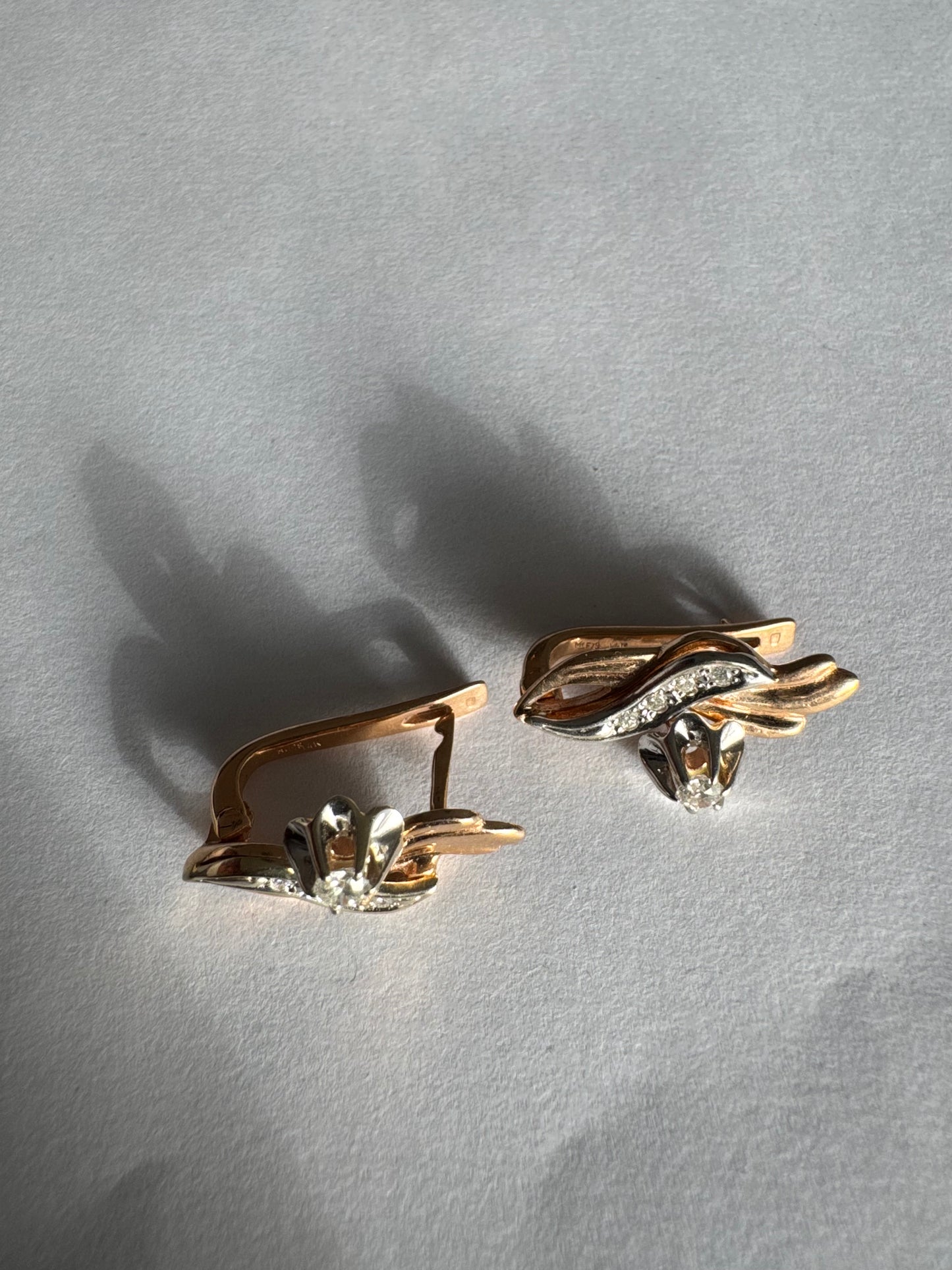 עגילי זהב 14 קראט בעיצוב מתעגל ואלגנטי המשובצים יהלומים נוצצים .