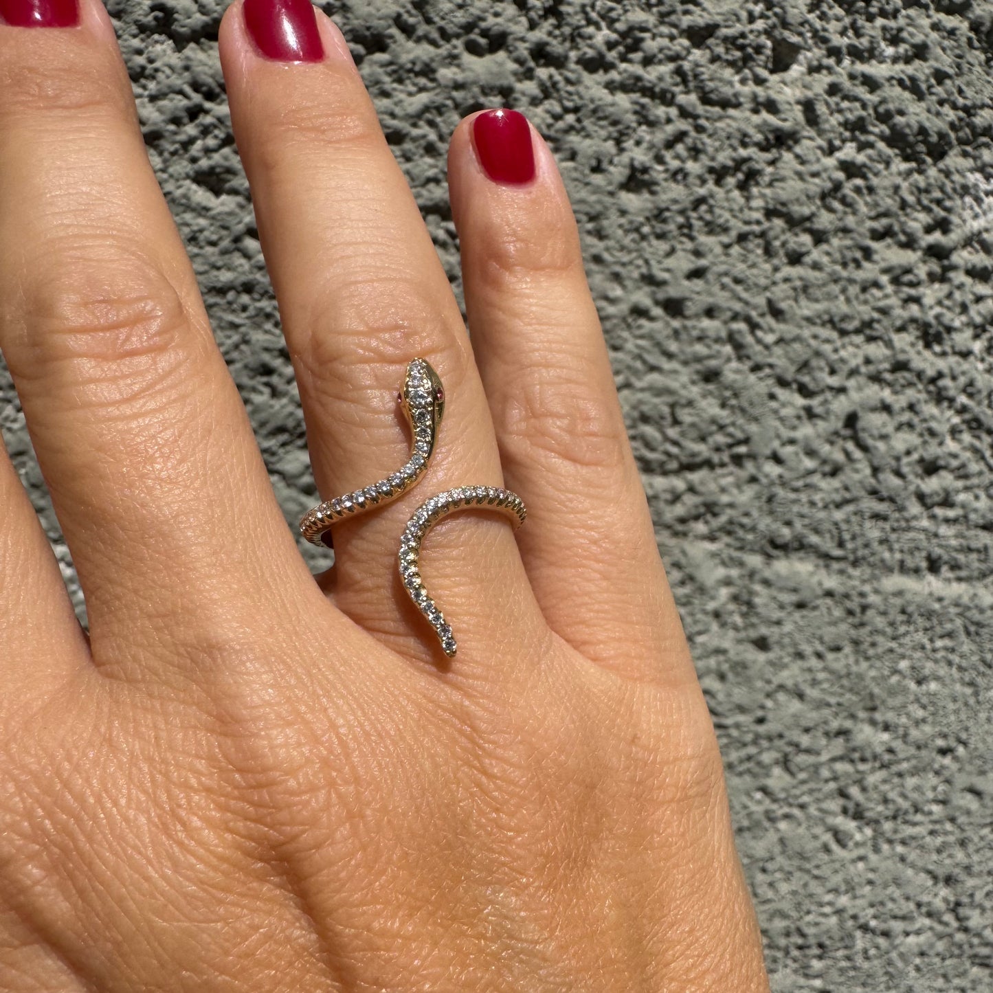 14K gold wrap-around snake ring, fully set with sparkling Diamonds along its body and head, finished with Rubies eyes