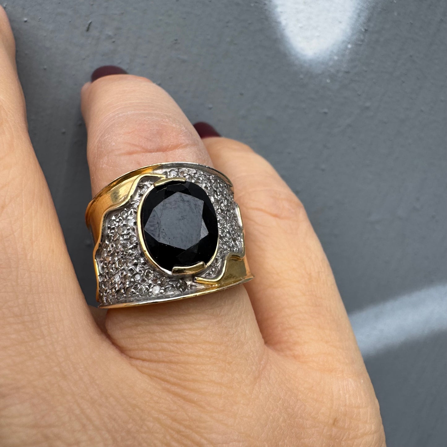 טבעת זהב צהוב 18 קראט משובצת יהלומים ואבן ספיר בצבע כחול כהה במרכז בעלת עיצוב דרמטי ואלגנטי בסגנון וינטג׳-יוקרתי