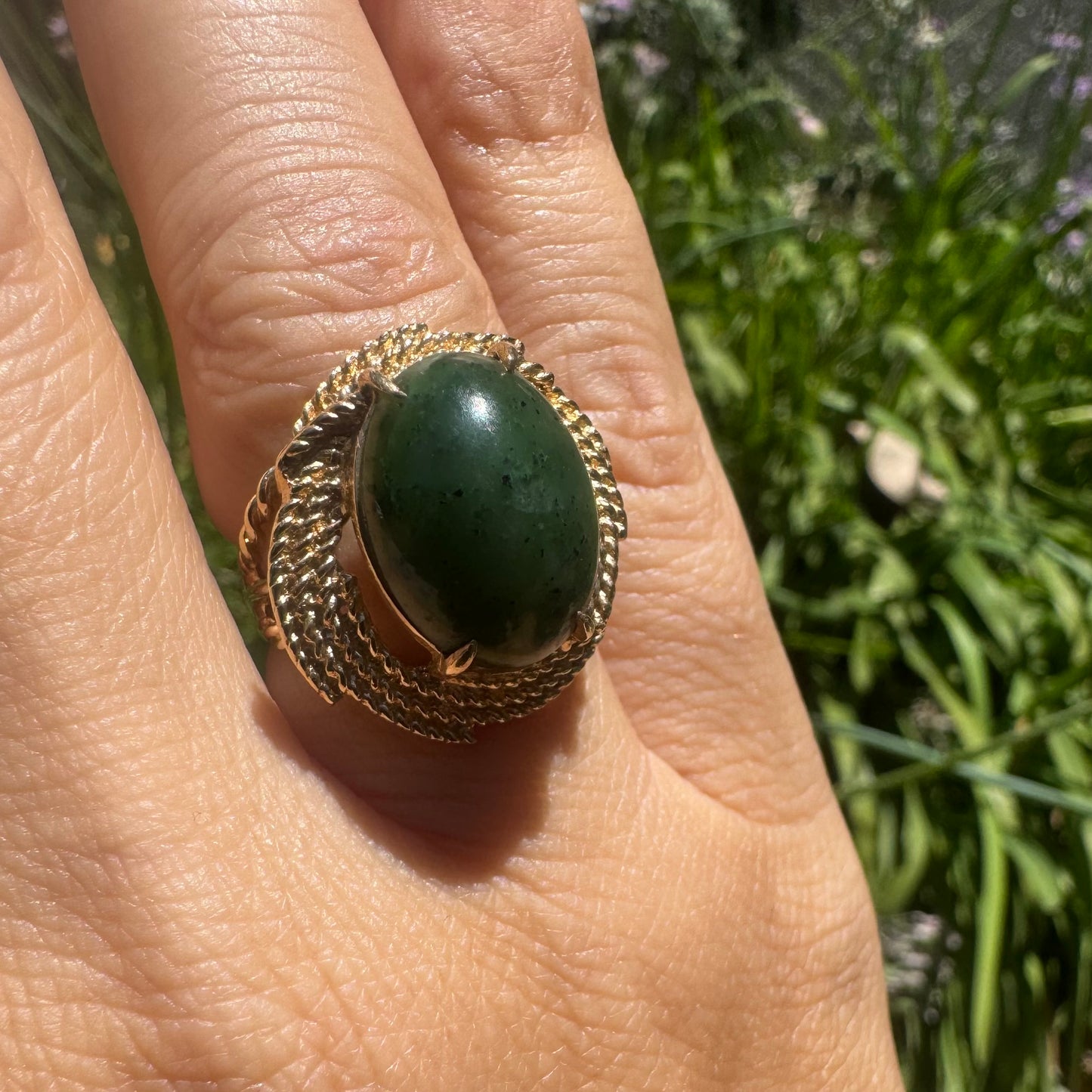 14K gold ring set with a deep green Jade set in a textured gold frame.