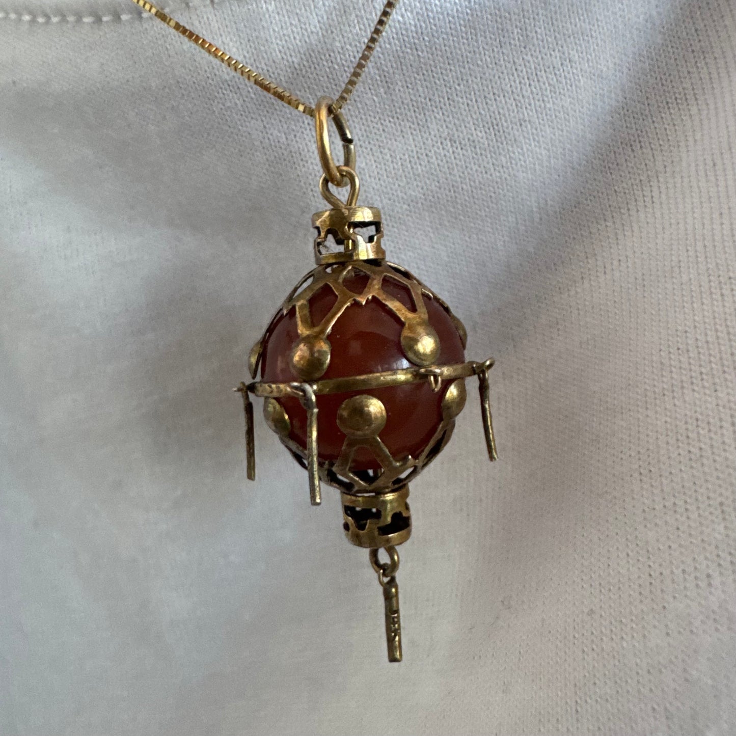 9K gold pendant set with a deep red stone in an intricate openwork design.