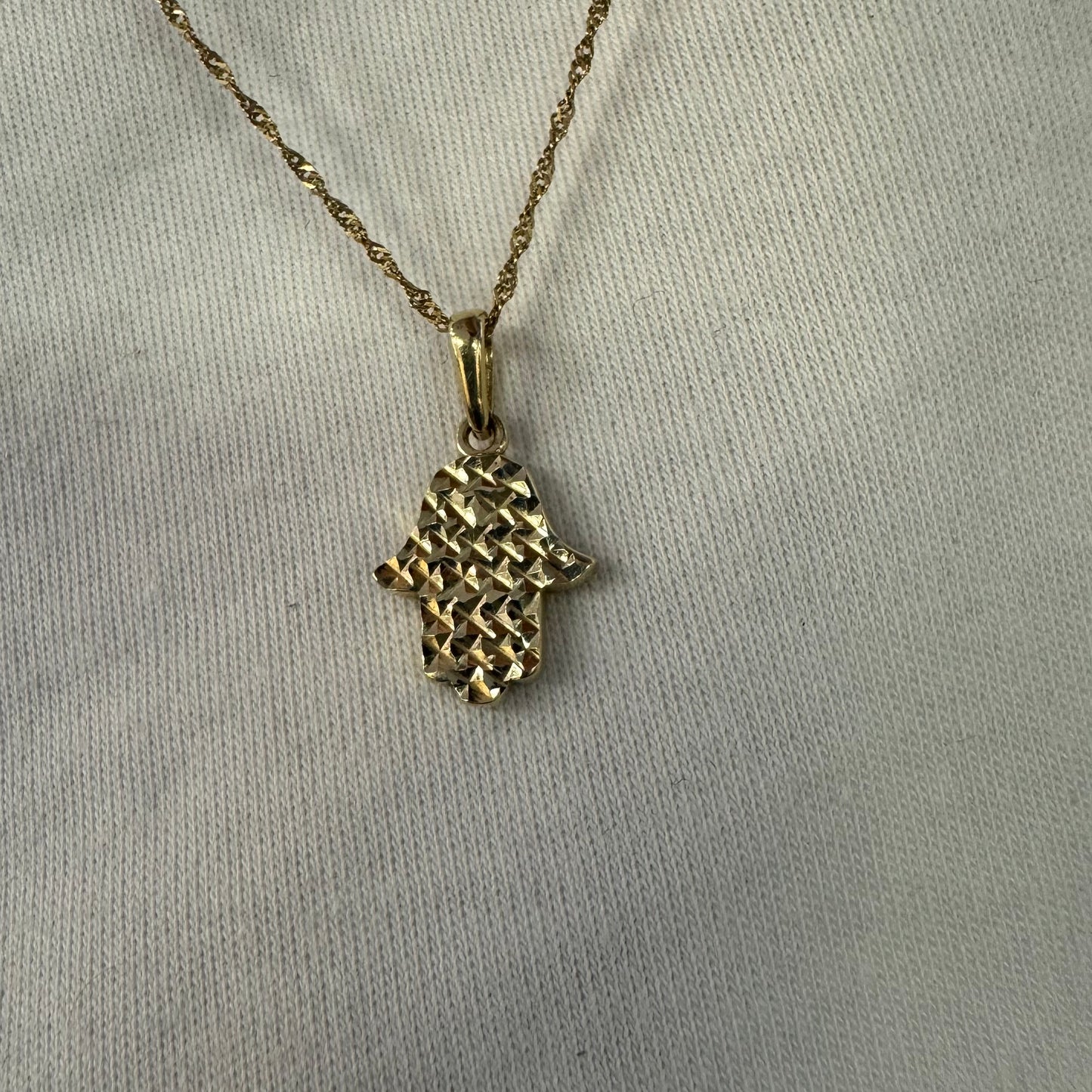 14K gold Hamsa pendant featuring a richly textured, light-catching finish.