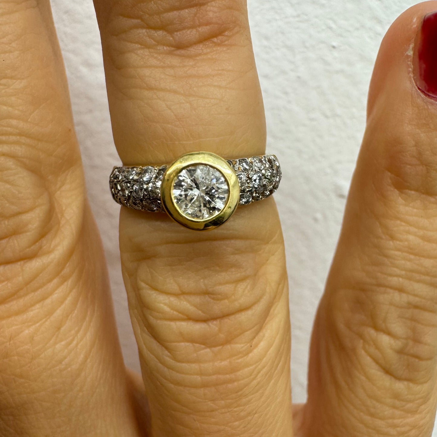 טבעת זהב צהוב 14 קראט משובצת יהלום עגול ויהלומים נוספים על הרצועה.