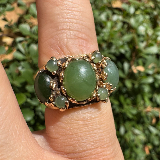 14K gold ring set with a central oval green Jade cabochon, framed by additional Jade stones in varying shades and sizes