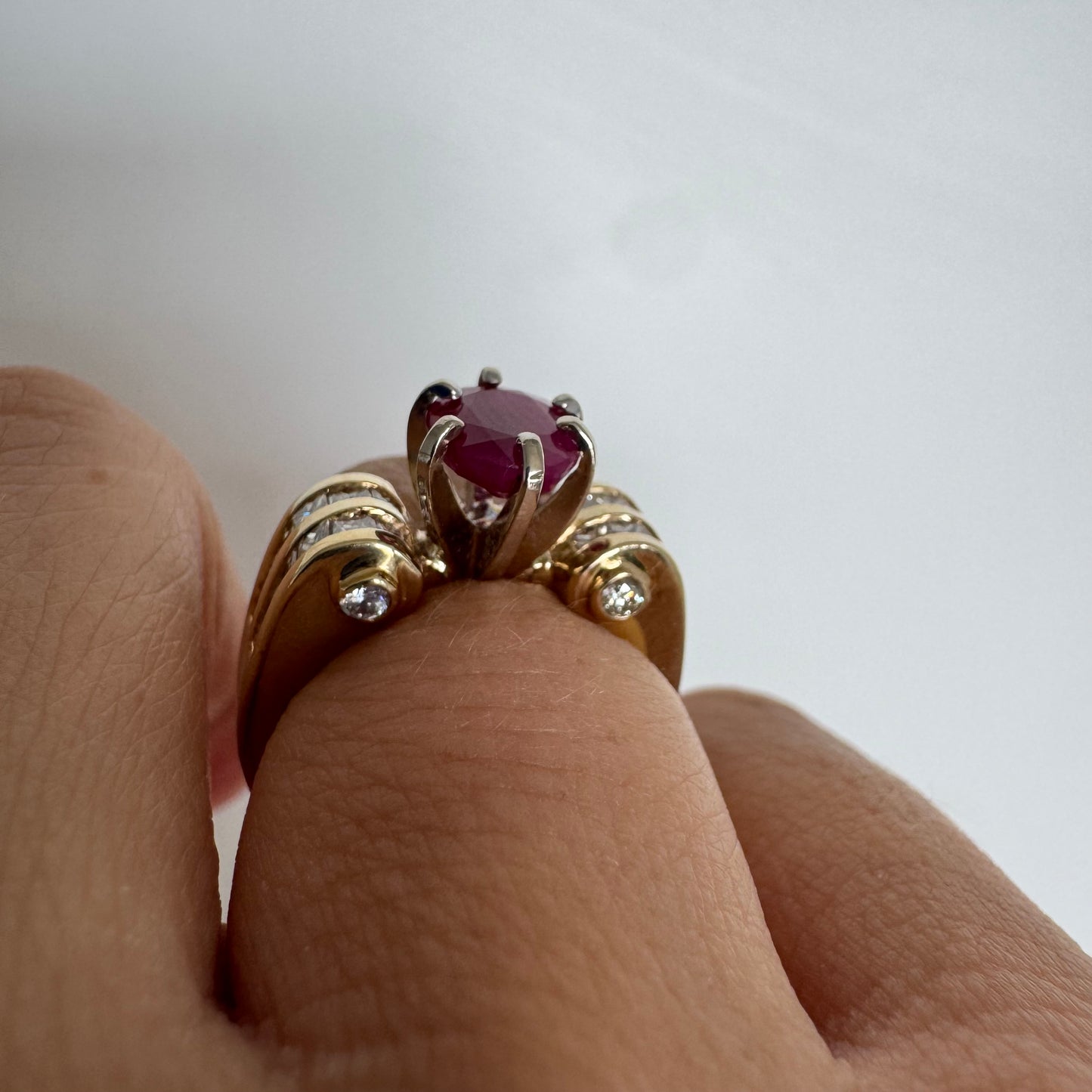 14K gold ring set with a vivid natural Ruby at the center and accented by rows of Diamonds on both sides.