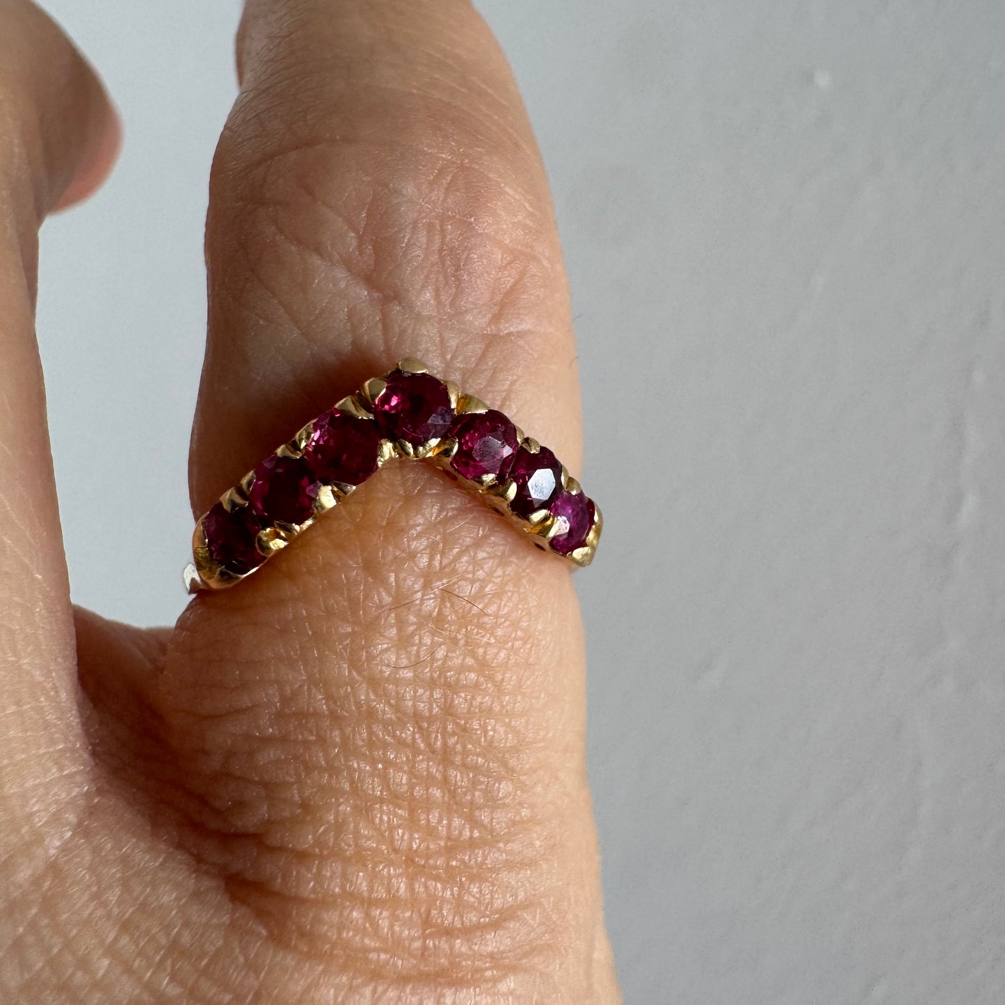 18K gold ring set with vivid red rubies in a distinctive V-shaped design.