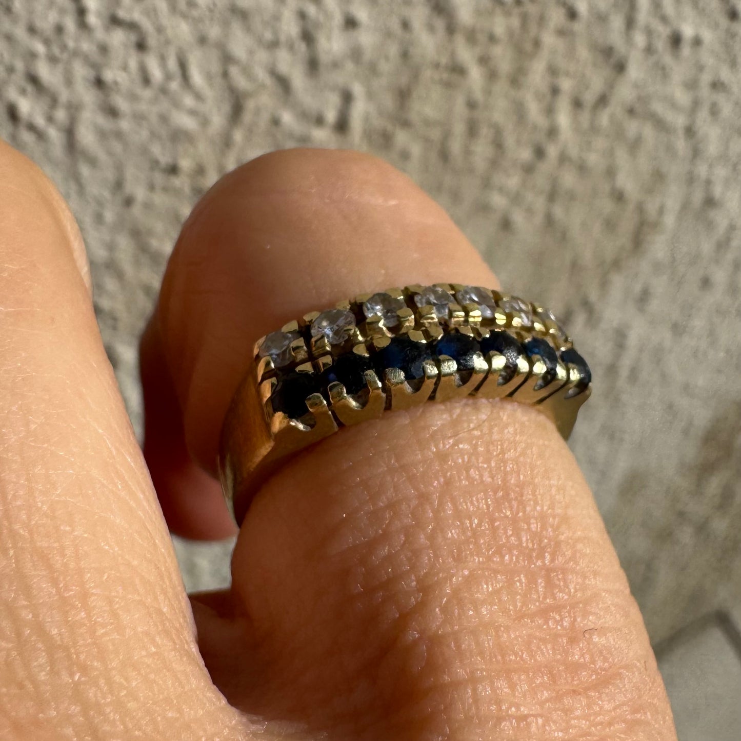 טבעת זהב צהוב 14 קראט, עם שורה של יהלומים נוצצים ושורה נוספת של ספירים כחולים.