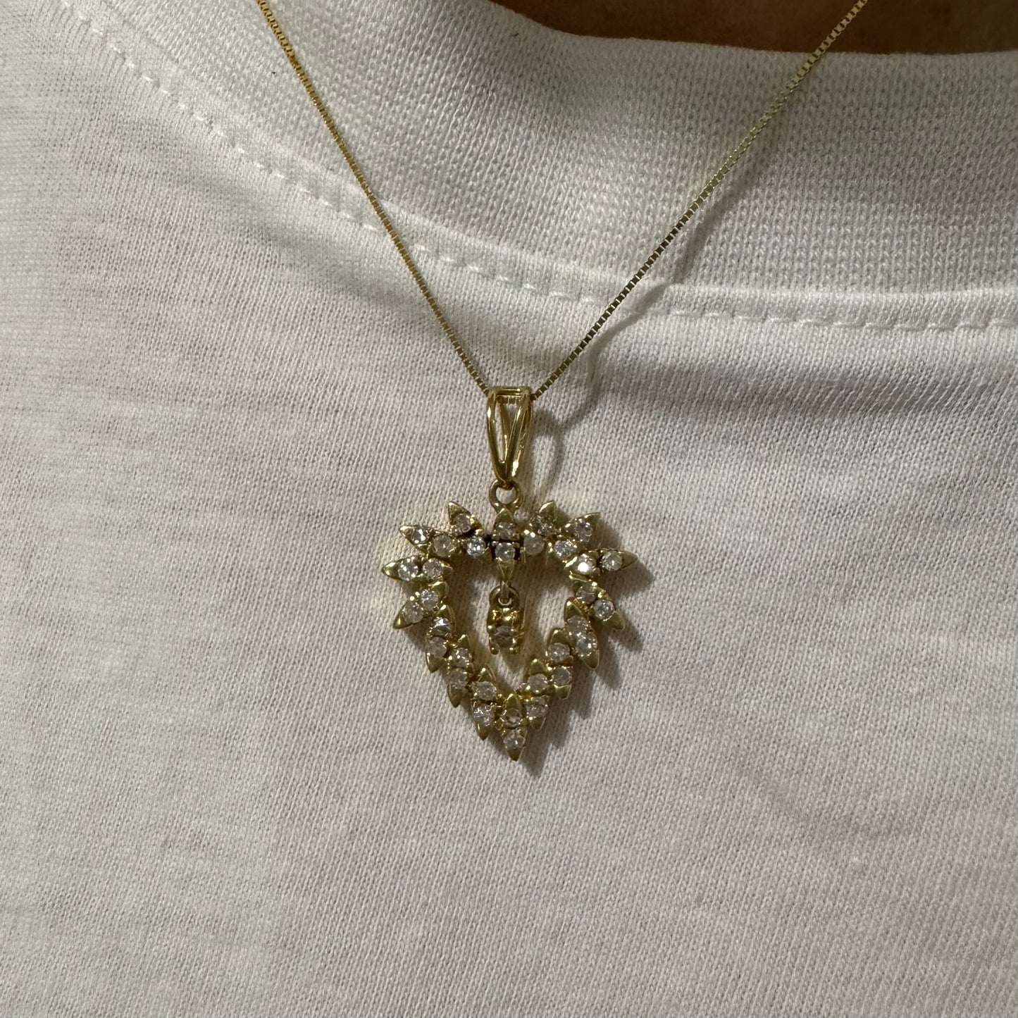 תליון זהב צהוב 14 קראט בצורת לב, משובץ יהלומים בסידור עדין היוצר מראה עשיר ומלא ברק.