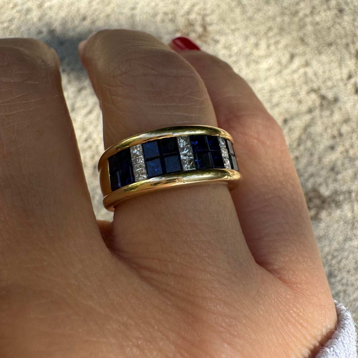 טבעת ה.שטרן זהב צהוב 18 קראט, בעיצוב רחב ומרשים. משובצת שורת אבני ספיר כחולות מרובעות בשילוב מחיצות של יהלומים לנגיעת ברק יוקרתי.