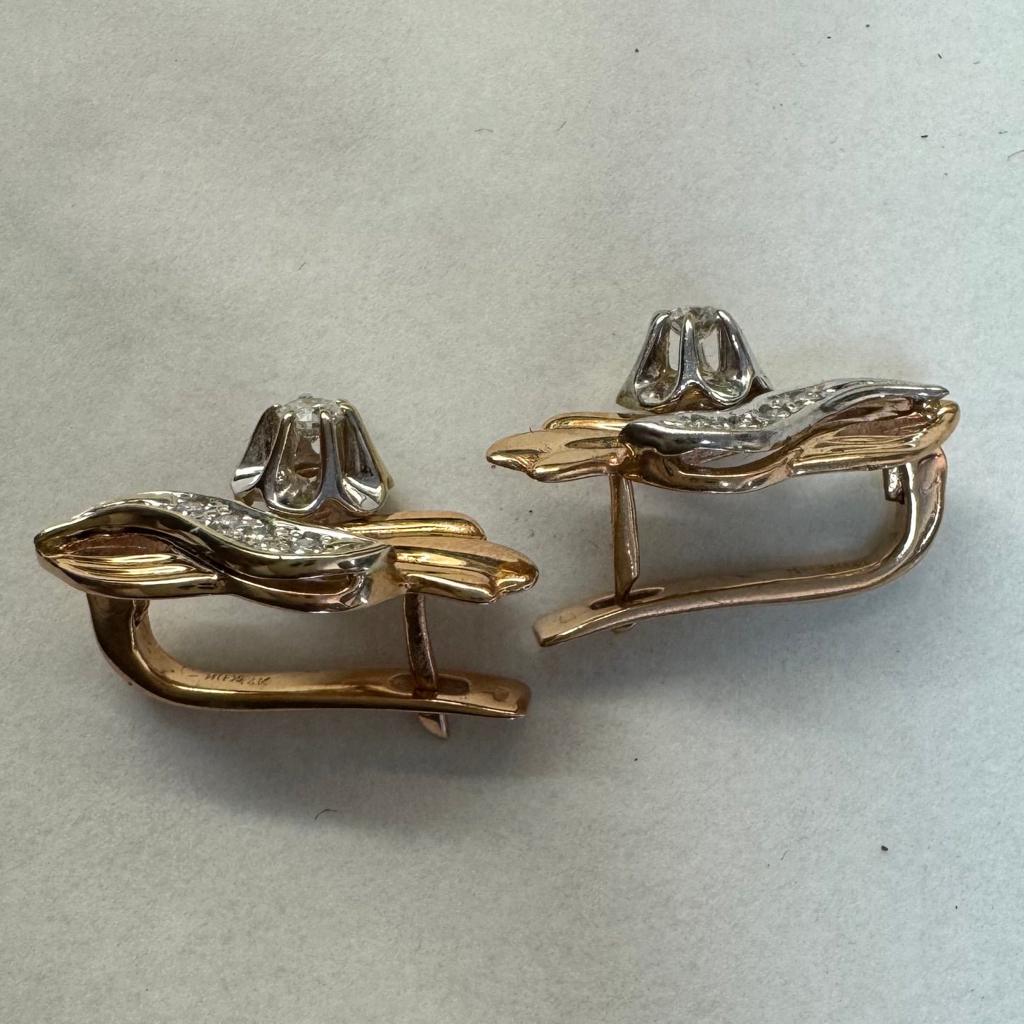 עגילי זהב 14 קראט בעיצוב מתעגל ואלגנטי המשובצים יהלומים נוצצים .