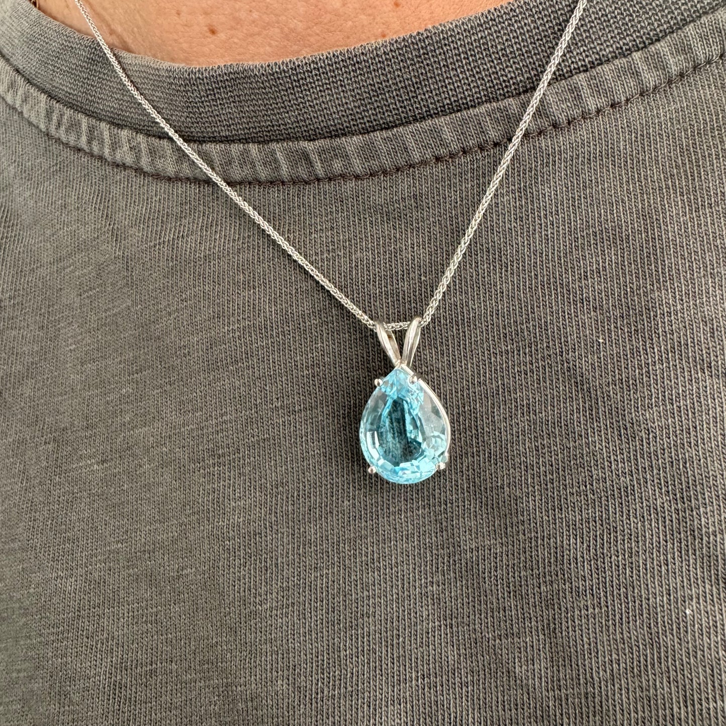 תליון זהב לבן 14 קראט המשובץ אבן טופז כחולה בחיתוך טיפה.