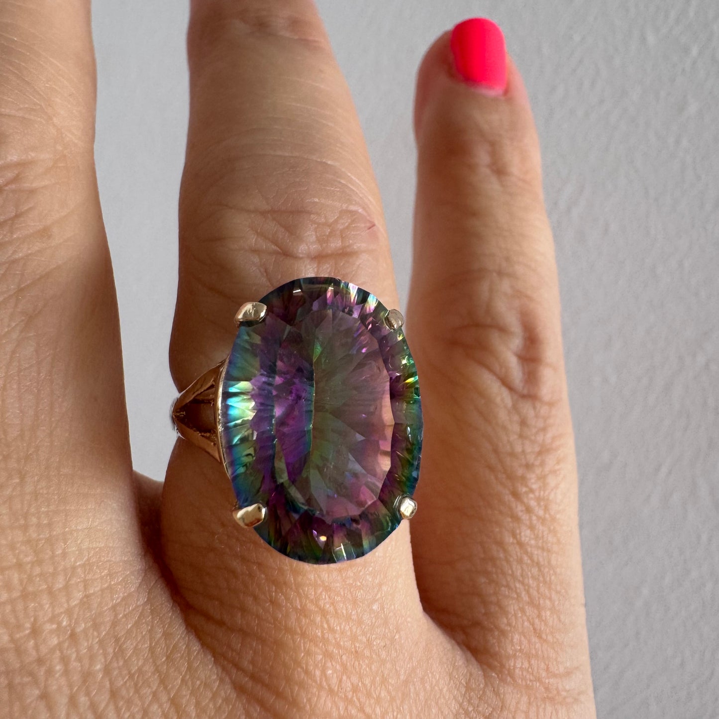 9K gold ring set with a large iridescent stone displaying mesmerizing shades of purple, green, and blue that shift beautifully in the light.