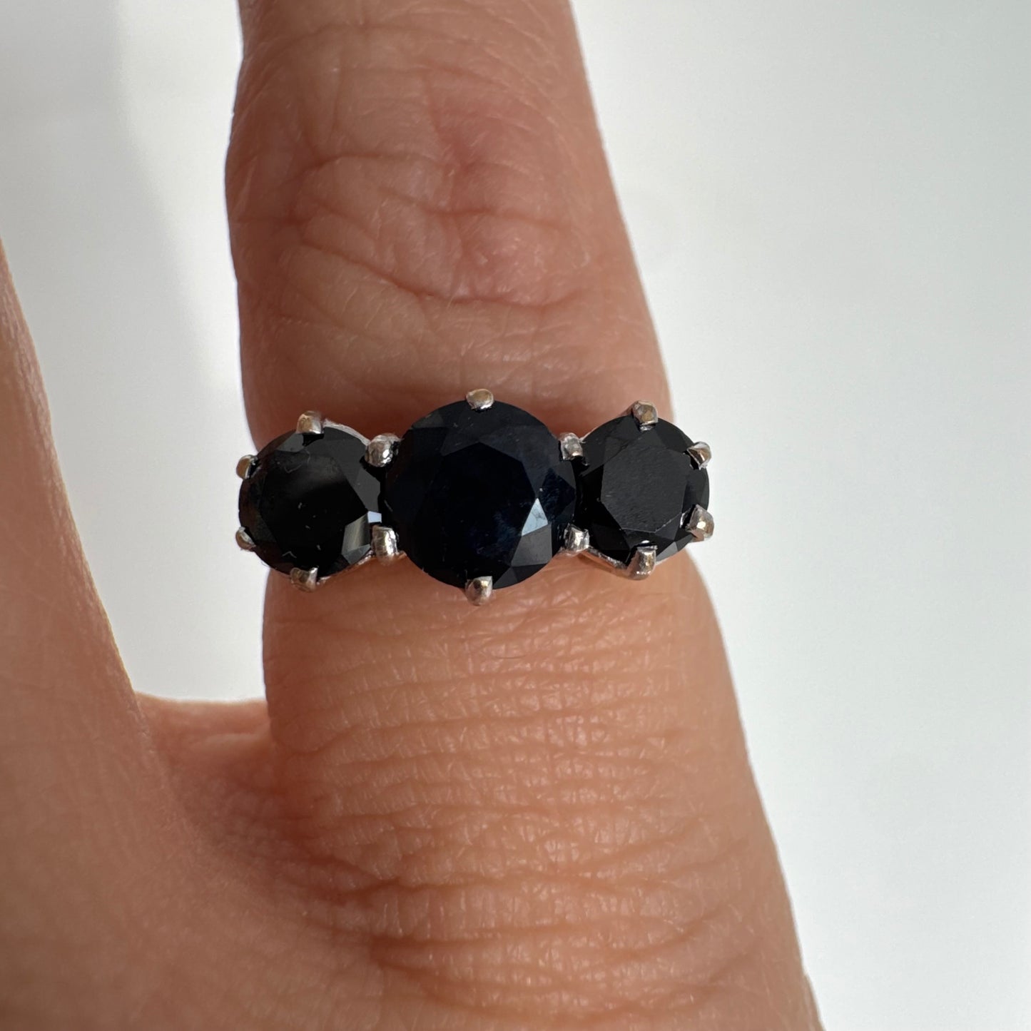 טבעת זהב 10 קראט משובצת שלוש אבני ספיר בצבע כחול כהה בחיתוך עגול, בעיצוב קלאסי עם נוכחות עמוקה ואלגנטית.