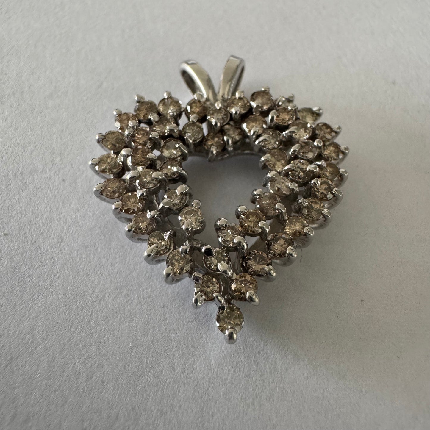 תליון לב זהב לבן 14 קראט, משובץ יהלומים בשיבוץ שיניים עדין היוצר מראה עשיר ומלא ברק.