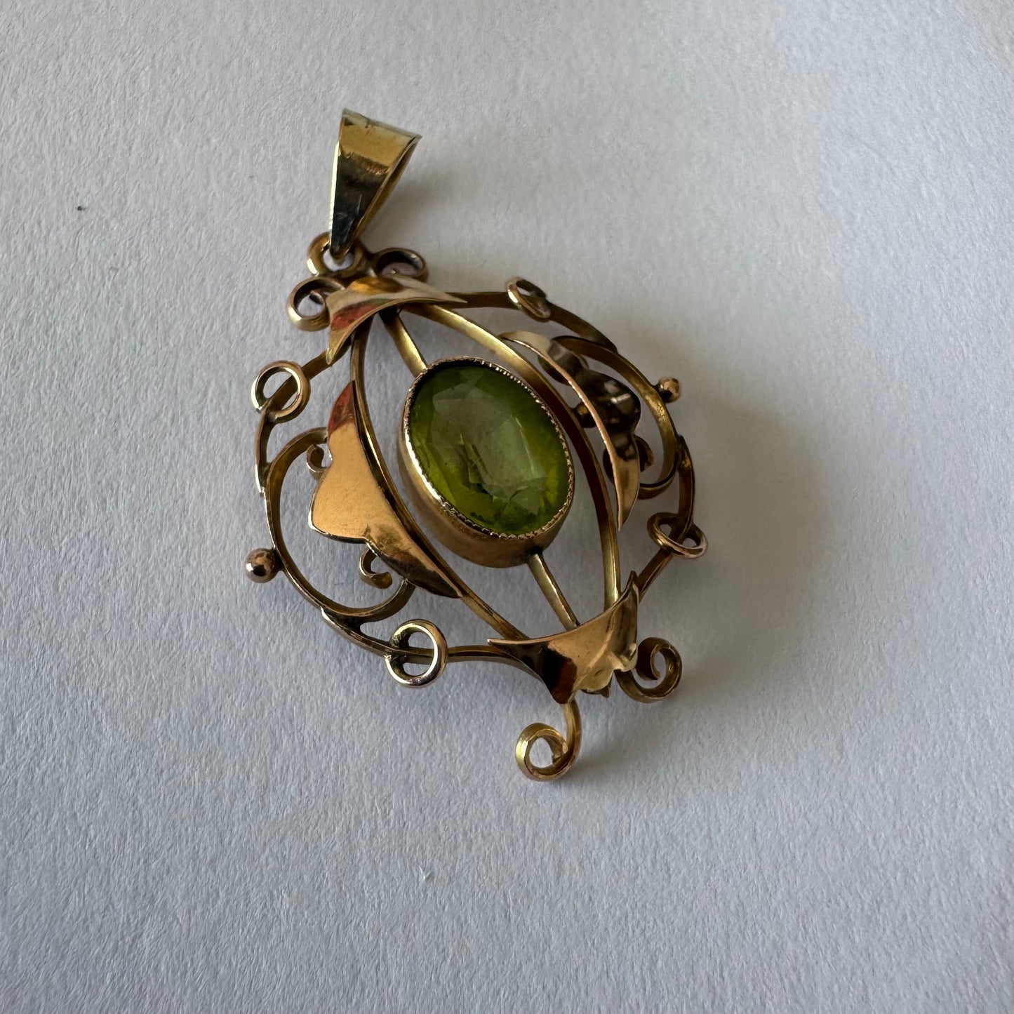 9K gold pendant featuring an oval-cut Peridot in a vibrant green hue.